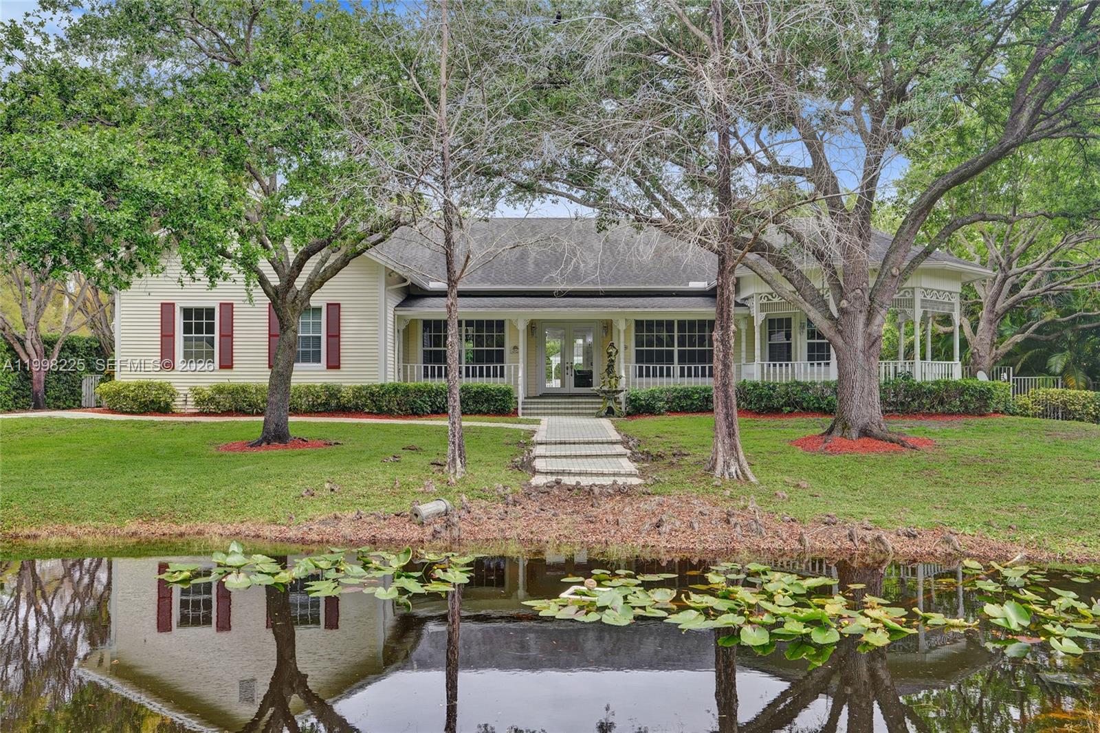 Timeless charm meets estate-style living on a builder’s acre in sought-after Plantation Acres, tucked away on a quiet cul-de-sac. This beautifully maintained 3BR + office/den, 2BA home offers an open floor plan with soaring ceilings, abundant natural light, wood and tile flooring, and inviting yet elegant living spaces throughout.

The kitchen features granite countertops, newer SSappliances, ample cabinetry, and a center island that flows seamlessly into the main living and dining areas, ideal for both everyday living and entertaining. 
The additional office/den provides flexibility for remote work, guest space, or a private retreat. Split-bedroom layout with oversized primary suite, sitting area, and spa-like bath with soaking tub, separate shower, and dual vanities.
Wraparound porch, French doors, and expansive windows enhance the home’s warm, timeless character. 

The private backyard is a true retreat featuring a resort-style pool, large paved deck, and charming gazebo perfect for entertaining or relaxing. Surrounded by lush landscaping with pond frontage and canal views, offering exceptional privacy and a serene setting.

Ideally located near major highways, shopping, dining, and close to top-rated schools including American Heritage School.

A rare opportunity to own a property that blends space, privacy, and character in one of Broward’s most desirable acreage communities.