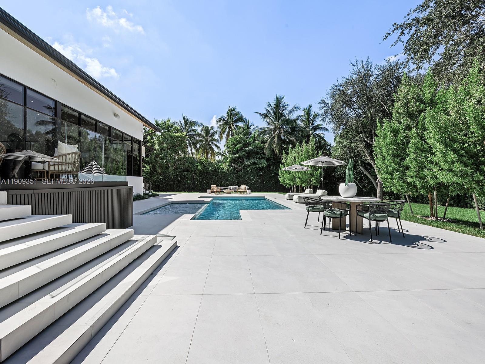 Elegantly reimagined and set on an expansive 30,997 SF lot in Phase I of Cocoplum, this stunning residence blends modern sophistication with timeless design. Located in a prestigious community offering voluntary HOA, 24/7 police patrol, and tennis courts just steps away. The 4-bedroom plus den, 4.5-bath home welcomes you through a custom mahogany pivot door into a luminous foyer where statement lighting and natural light create a warm, inviting ambiance. The open-concept layout offers exceptional flow, with most living spaces on the main level. Highlights include engineered wood flooring, an ItalKraft kitchen with Sub-Zero and Wolf appliances, induction range, dual undercounter fridge drawers, Ikunan bathrooms and closets, and a sleek porcelain fireplace centerpiece.