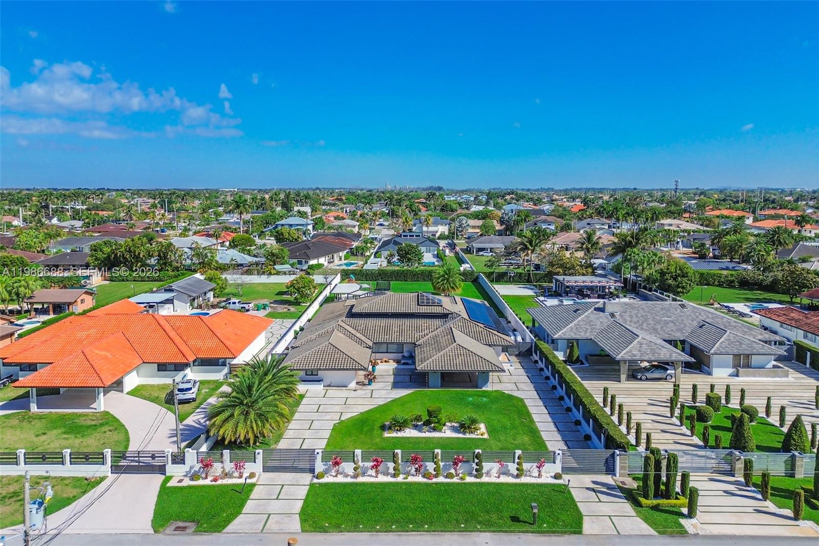 Welcome to this masterpiece of modern architecture! Experience the pinnacle of luxury in the prestigious JG Head's Farms, offering a resort-style lifestyle on a sprawling 27,000 sq. ft. lot with the rare freedom of NO HOA. Enclosed by a secure perimeter wall and private gates, a grand circular driveway leads to this immaculate estate. Inside, the open-concept design is bathed in natural light through massive impact windows. Top-quality finishes include gleaming porcelain floors and soaring double-height ceilings with rich wood accents. Entertain in the elegant formal dining room or relax by the stunning floor-to-ceiling illuminated onyx-style wall. The chef's kitchen is a showstopper, featuring premium black granite countertops with galaxy-style crystalline flecks, sleek custom cabinetry, and state-of-the-art appliances. The luxury extends to the primary suite with a custom-built walk-in closet, spa-inspired bathrooms with floating vanities, a dedicated exercise room, and a pristine laundry center. Outdoors, your tropical oasis awaits. Enjoy expansive covered terraces with an outdoor kitchen, perfect for al fresco dining. The beautifully manicured grounds center around a spectacular geometric pool, vast green spaces, and a private children's playground. Offering unmatched privacy yet immediate access to the Turnpike and FIU, this move-in-ready gem is the ultimate Miami retreat! Contact us today to schedule your private showing and discover this Miami paradise!