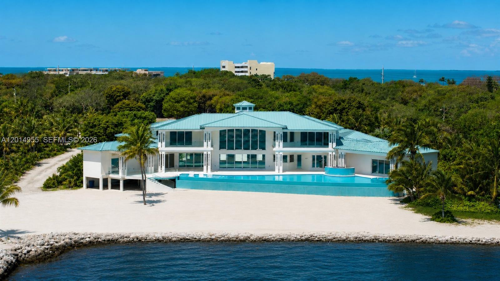 Set on over 2 acres along prestigious Millionaire’s Row in Tavernier, this newly constructed oceanfront residence offers an extraordinary blend of scale, design, and modern coastal luxury. Encompassing approximately 8,200 square feet under air and over 16,000 total square feet, the home was thoughtfully designed for elevated living and grand-scale entertaining. The property features 5 bedrooms, 6 full baths, and 2 half baths, with all bedrooms offering en suite accommodations, custom closets, and refined finishes throughout. Additional highlights include a private office, elevator, whole-home sound system, 600-amp electrical service, and five independent AC zones. Interiors are curated with white diamond marble, rich teak wood flooring, custom millwork, and a striking steel roof. The chef’s kitchen is outfitted with premium Wolf, SubZero, and Cove appliances, dual dishwashers, farmhouse sinks, and custom mahogany countertops. With 240 feet of direct ocean frontage, outdoor living is equally impressive, anchored by a 120-foot resort-style pool with heating and chilling systems, a gas-heated spa, summer kitchen, cabana bath, and expansive covered entertaining areas. Additional features include a 3-car garage, climate-controlled workshop, and weekly rental zoning, offering both exceptional lifestyle appeal and investment potential.