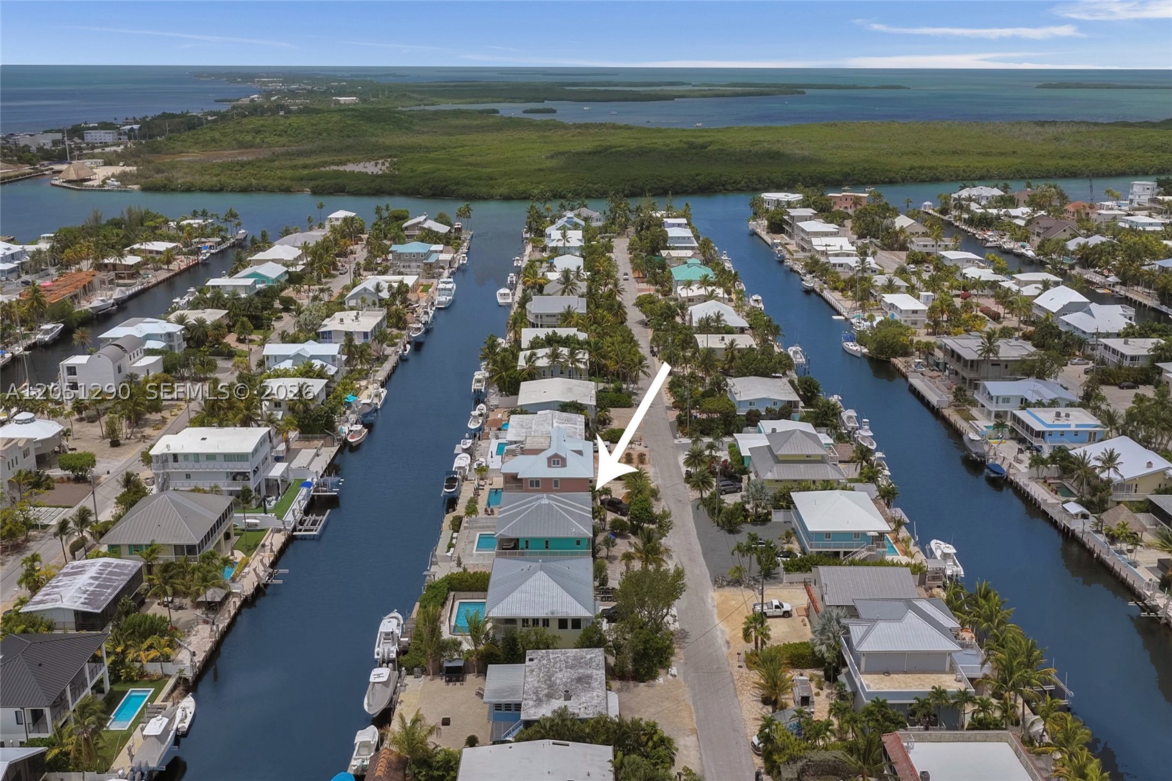 OCEAN ACCESS WATERFRONT OPPORTUNITY IN VENETIAN SHORES! Immaculate 2-story CBS concrete home offering the ultimate Florida Keys lifestyle! Situated on a 100' wide deep-water canal with NO FIXED BRIDGES and direct access to both the Atlantic Ocean and Florida Bay via Snake Creek, this is a boater's dream. Minutes to open water with a private dock featuring power and davits, perfect for large boats.  This spacious home features 3 bedrooms, 2.5 baths with a flexible floor plan. The first floor offers 2 bedrooms, 1 full bath, family room, and bar area, while the second floor features the primary suite, oversized kitchen, dining room,  laundry room, and half bath to maximize the spectacular waterfront views. Enjoy breathtaking sunsets and tropical breezes from the expansive wraparound covered porch.  Additional features include beautiful hardwood floors, an oversized kitchen ideal for entertaining, brand-new saltwater pool (2026), three large exterior storage rooms, circular driveway, and fresh exterior paint (2025). Lovingly maintained and in immaculate condition, this home is ready for your personal updates to create the ultimate Keys retreat.  Located in the highly desirable Venetian Shores community, known for its deep, wide canals, outstanding boating access, and optional homeowners association.   Whether you're looking for a full-time residence, weekend getaway, or luxury waterfront escape, this is a rare opportunity to own in one of Islamorada's premier boating communities.