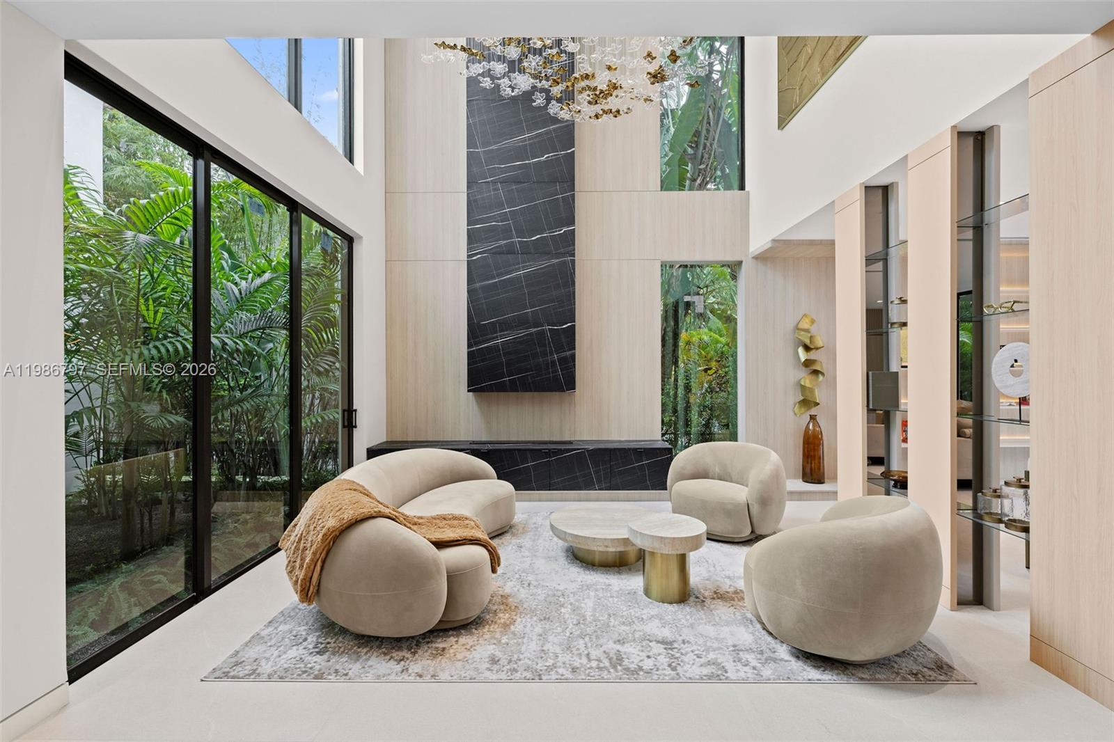 Welcome to the Modani Residence, a showcase of modern design and turnkey luxury in the heart of Miami Beach. This stunning five-bedroom home is offered FULLY FURNISHED with Modani furniture and thoughtfully curated designer finishes throughout, with a serene atmosphere created by neutral palettes and greenery. A grand atrium-style entry with a striking staircase sets the tone upon arrival. The main level features open-concept living, connecting the formal living room with double-height ceilings, family room, dining area, and chef’s kitchen. The kitchen is equipped with premium Miele appliances, including a gas range stovetop, dual dishwashers, refrigerators, and sinks. A first-floor bedroom adds flexibility for guests or office use, while laundry is located in the garage. The home also offers a two-car garage and a large driveway with a coral stone design. Upstairs, four generously sized bedrooms each feature ensuite bathrooms and custom built-ins. Two bedrooms open to a front-facing balcony overlooking the front yard, while another sits privately to the side. The expansive primary suite overlooks the backyard and pool, complete with its own balcony, a large custom walk-in closet, dual vanities, and a separate tub and shower. The backyard is designed for entertaining, with a large pool, cabana bathroom, and patio area. A truly one-of-a-kind residence, offered fully furnished for a turnkey lifestyle with a sense of calm, design, and distinction.