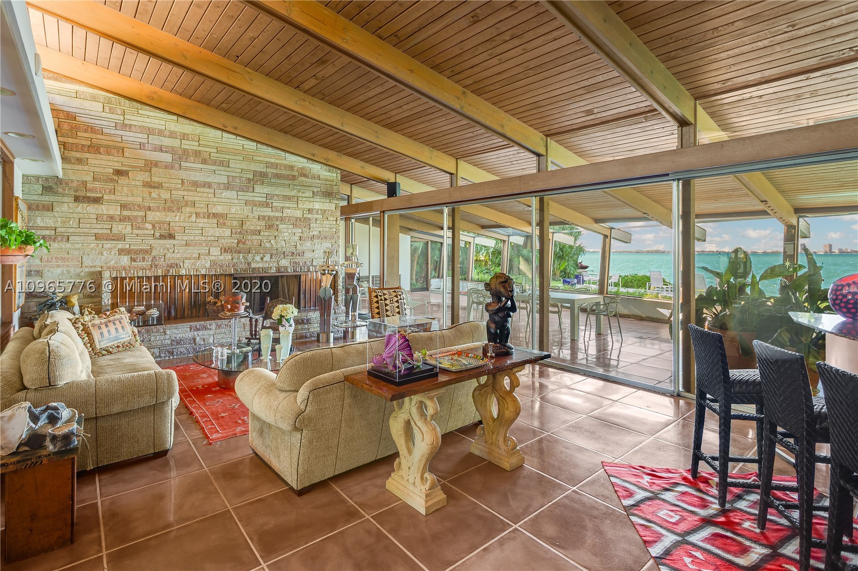 True mid century modern gem located on the most sought after location of prestigious North Bay Rd. Enter into this unique architecturally designed home surrounded by lush landscaping through wooden gates and an open foyer entry where you will find high ceilings and great walls for art throughout. The functional indoor outdoor living make it the perfect home for entertaining. Enjoy the bay breeze and breathtaking sunset views from the outdoor oasis that offers over 100+ ft of water frontage and unobstructed bay views.