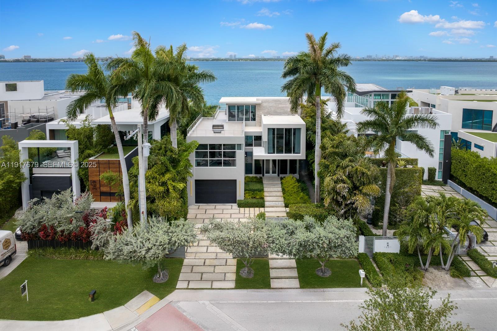 Experience the ultimate blend of waterfront serenity & modern luxury in this 5BD/5BA masterpiece, inspired by earthy sophistication. Enjoy 60' of open bay water frontage, a heated saltwater Infinity-edge pool & outdoor lounging areas. Grand open living spaces transition effortlessly to the outdoors, creating an ideal setting for entertaining. A sleek sunroom with floor-to-ceiling glass captures natural light & opens to an expansive rooftop terrace. Inside, the chef’s kitchen is outfitted with Taj Mahal quartzite, a custom island, bespoke cabinetry & Subzero/Wolf appliances. Travertine-clad walls & ambient-lit stairs frame the foyer. Primary suite features custom millwork, infinity leather-wrapped panel & steam shower. RH furnishings & curated finishes complete this one-of-a-kind residence.