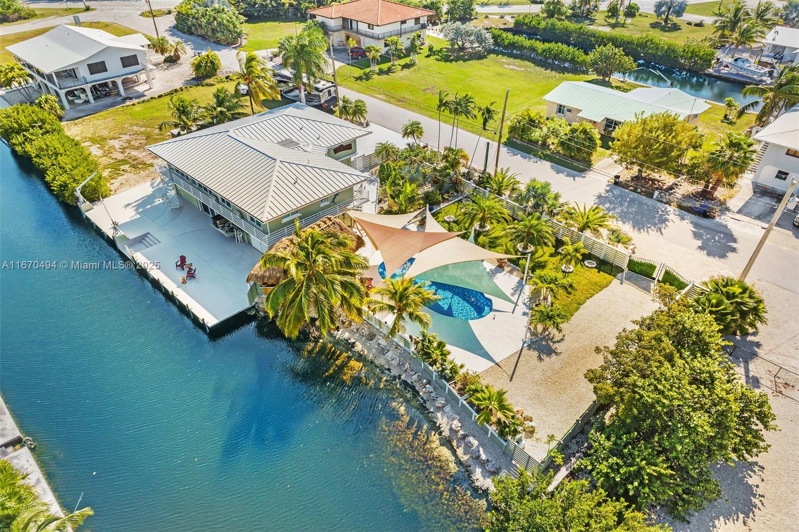 PRICED TO SELL! Don't miss out on this incredible value where you'll feel as if you're in your own tropical resort. A short canal ride under the Watson Bridge puts you in Bogie Channel leading to superb fishing and diving in the ocean or back country. The double lot totals over 1/3 acre with a 75 ft. concrete dock and boat davits directly behind the home. If you enjoy kayaking, imagine the feeling of calmness as you paddle through the peace and quiet of nearby mangroves. How important is solid construction to you? Built like a fortress, this impressive 3-bedroom, 2-bath CBS home has poured concrete floors, impact-resistant windows and doors, and a recent 24 gauge standing seam metal roof. Check out the extra-large ground level enclosure!