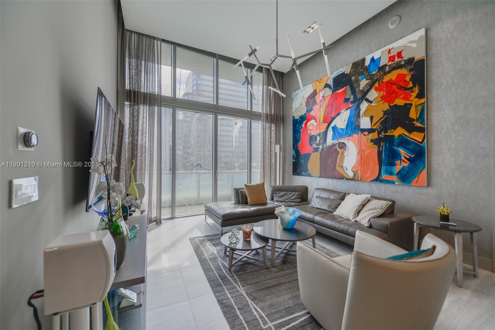 This apartment was renovated with exquisite attention to detail. It features elegant Spanish porcelain floors with soundproofing, freshly painted walls with designer wallpaper accents, and custom drop ceilings in the bedrooms, bathrooms, and living areas. The space is highlighted by impressive double-height ceilings that invite natural light, complemented by dimmable LED fixtures throughout, creating a warm and modern ambiance. It also includes new electric curtains and blackout shades, a fully remodeled kitchen with premium cabinetry and appliances—refrigerator, dishwasher, garbage disposal, microwave, washer, and dryer—and upgraded bathrooms with new vanities, toilets, faucets, and showers. A perfect blend of modern design and timeless style. Leasing permitted 2x/year (6-month min). Deeded parking space included.