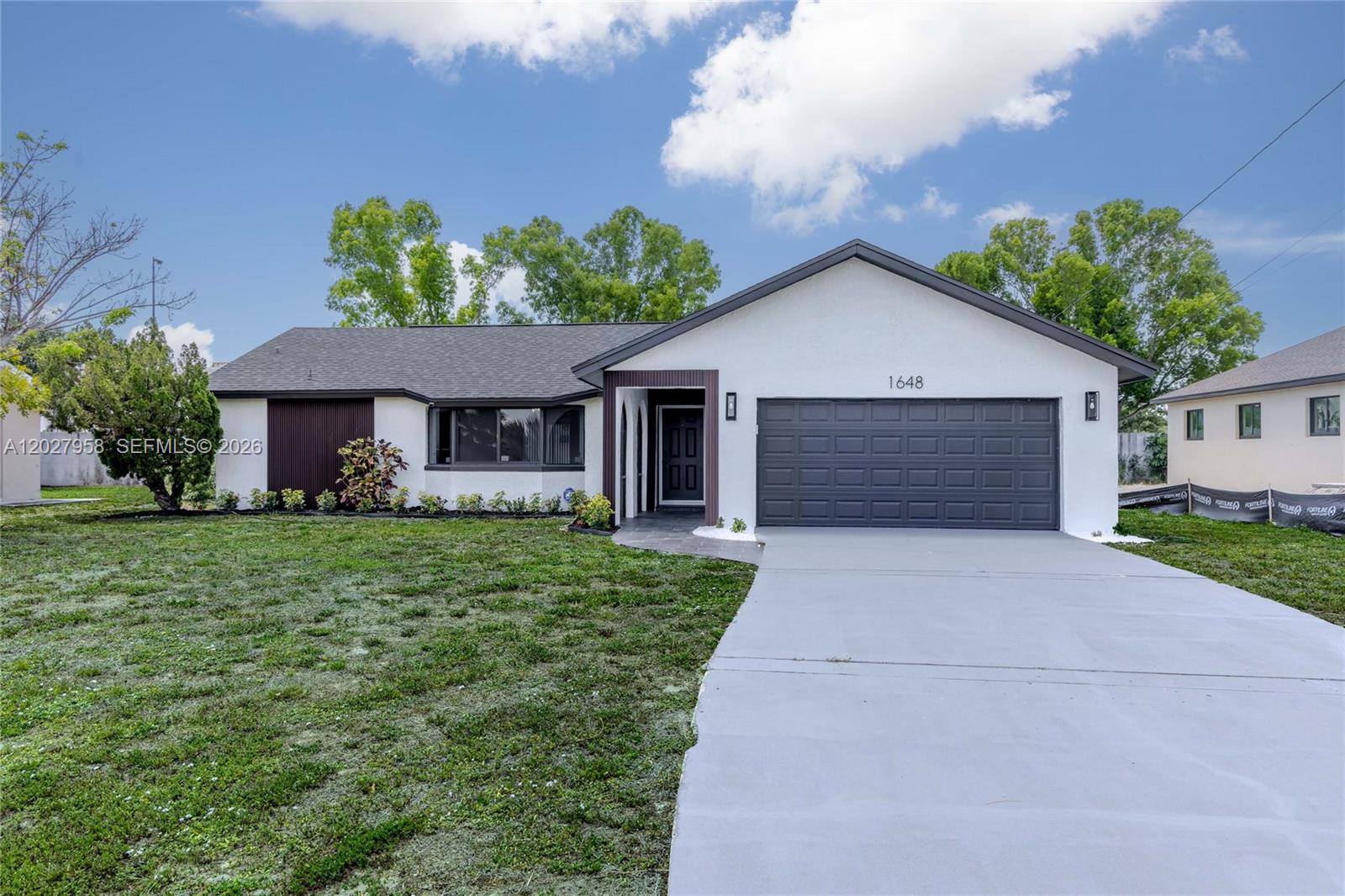 Welcome to a turnkey designer remodel in the heart of Cape Coral. Every inch of this 3-bedroom, 2-bath home has been reimagined, with every dollar of work completed under proper City of Cape Coral permits. Move in, unpack, and start living.
All-new hurricane impact windows and doors deliver storm protection and insurance savings, paired with a new roof and new A/C for true peace of mind. There is no HOA, no monthly fees, and all City of Cape Coral assessments are paid in full.
Inside, a bright open layout flows across glossy marble-look porcelain tile under brand new designer LED lighting throughout, with no carpet anywhere. The fully remodeled kitchen features white shaker cabinetry, veined quartz countertops, stainless appliances, and a breakfast bar opening to the main living space. A stunning custom slat-wood media wall with electric fireplace and a brand new 75-inch TV anchor the living area and stay with the home.
Both bathrooms deliver true spa-level finish with floor-to-ceiling marble-look tile, frameless glass, smart LED mirrors, and matte black fixtures. The 2-car attached garage and expansive open backyard offer room to grow — perfect for a future pool or outdoor retreat. Fresh interior and exterior paint complete the package.
And then there's the location — walk to Walmart, Publix, restaurants, and shopping right from your front door. Homes finished to this level, with this combination of new systems and walkable convenience, are rare at this price.