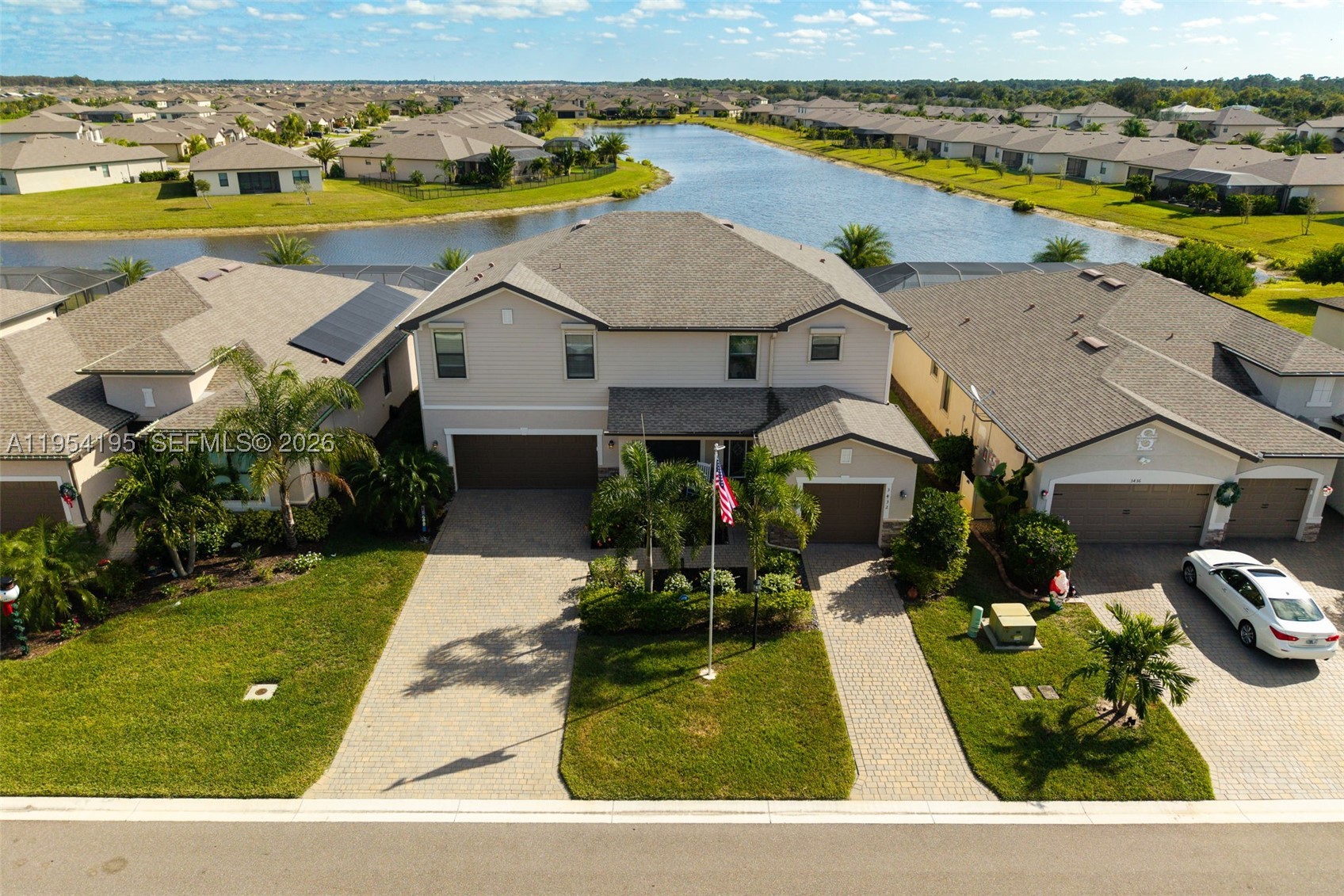 This striking lakefront home in Portico impresses from the moment you walk in and continues to impress daily. Set on one of the community’s most breathtaking long-lake lots, this five-bedroom plus loft, four-and-a-half-bath pool home offers space, flexibility, and stunning water views from sunrise to sunset. Built in 2021, the Sorrento floor plan features an open main level with wood-look tile, crown molding, and a central kitchen with white cabinetry, granite counters, stainless appliances, extended dining cabinetry, and a wine cooler. A full first-floor guest suite with pool access is perfect for guests or multigenerational living. Outside, the oversized lanai with custom pavers overlooks the heated pool and wide water views, with motorized hurricane-rated Kevlar screens. Upstairs, four bedrooms and a flexible loft add space, while upgrades like epoxy garage floors, insulated doors, whole-house water softener, and designer lighting enhance move-in readiness. Located in an X flood zone requiring no flood insurance and equipped with impact-rated windows and shutters, this gated Portico home offers peace of mind and access to a clubhouse, pool, courts, fitness room and play are, all minutes from shopping and dining.