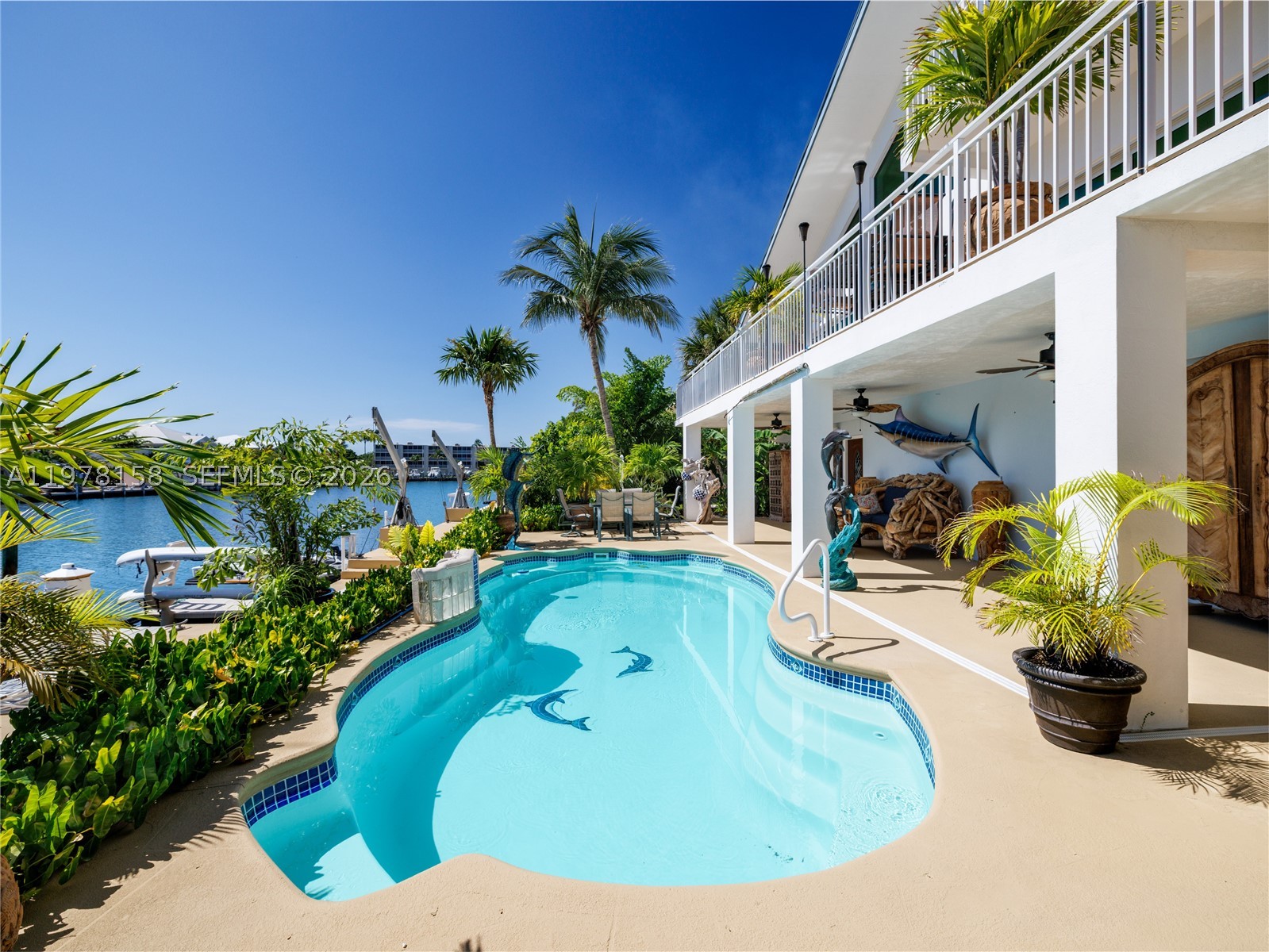 A rare waterfront estate along a 200-foot wide canal with a 110-foot dock and direct ocean access, capturing the essence of Florida Keys living. Spanning over 3,200 square feet, this residence features four bedrooms and three-and-a-half baths, ideal for hosting family and guests in true island style.
Inside, a dramatic grand staircase and soaring two-story great room create an inviting yet refined atmosphere. Walls of windows frame tranquil water views and fill the space with natural light, providing the perfect setting for entertaining or relaxing after a day on the water. The kitchen offers granite countertops, stainless steel appliances, and an open layout that seamlessly connects the living and dining areas.
Outside, your private waterfront retreat awaits. The 110-foot concrete dock with dual 40-foot finger piers provides exceptional deep-water dockage for multiple vessels, including large yachts, with quick Atlantic access. Boaters will appreciate the floating jet ski and kayak docks, davits, fish-cleaning station, and ice machine.
Surrounded by lush tropical landscaping, the heated pool and spa create a secluded oasis where island breezes and sunshine define everyday living. Whether enjoying mornings on the water, afternoons poolside, or evenings under the stars, this property delivers the luxury and lifestyle of the Florida Keys.