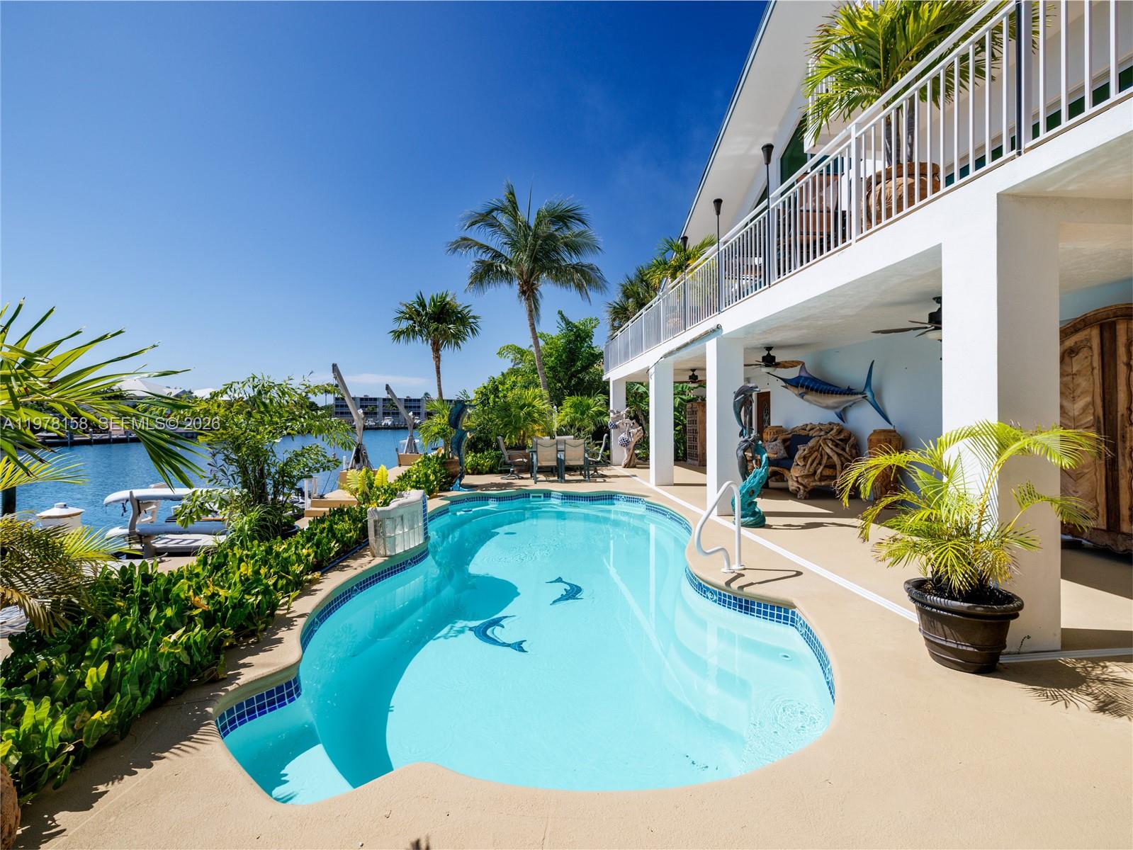 A rare waterfront estate along a 200-foot wide canal with a 110-foot dock and direct ocean access, capturing the essence of Florida Keys living. Spanning over 3,200 square feet, this residence features four bedrooms and three-and-a-half baths, ideal for hosting family and guests in true island style.
Inside, a dramatic grand staircase and soaring two-story great room create an inviting yet refined atmosphere. Walls of windows frame tranquil water views and fill the space with natural light, providing the perfect setting for entertaining or relaxing after a day on the water. The kitchen offers granite countertops, stainless steel appliances, and an open layout that seamlessly connects the living and dining areas.
Outside, your private waterfront retreat awaits. The 110-foot concrete dock with dual 40-foot finger piers provides exceptional deep-water dockage for multiple vessels, including large yachts, with quick Atlantic access. Boaters will appreciate the floating jet ski and kayak docks, davits, fish-cleaning station, and ice machine.
Surrounded by lush tropical landscaping, the heated pool and spa create a secluded oasis where island breezes and sunshine define everyday living. Whether enjoying mornings on the water, afternoons poolside, or evenings under the stars, this property delivers the luxury and lifestyle of the Florida Keys.