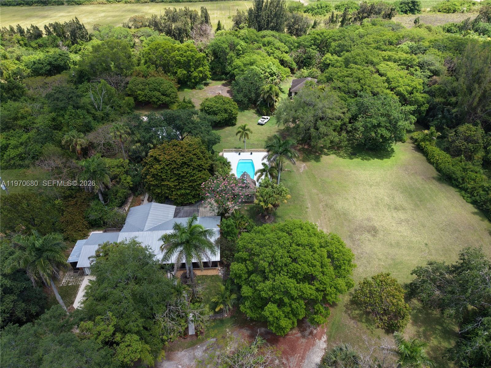 Stunning, unique, well maintained, fully fenced, Redland 5 acre Compound consisting of two homes, partially located in a gorgeous rare Hammock of trees and plenty of cleared land. Main house is a 4/3 which includes a large studio apartment with a separate driveway, entrance and yard. The guest house is a detached 2/2 in the back of property. Huge Detached CBS 2 Car Garage, Pole Barn, Salt Water Pool, Chickee Hut and RV Slab with Utility Hook Up. Three separate electrical meters. There is a lot of parking space. Enjoy the good life and relax as you sit in your Chickee Hut facing the pool and watching Hummingbirds circle among mature flowering plants and trees. Quaint coral rock wall and embellishments. Lots of room for planting, nurseries and horses. Lucrative property. AG TOURISM IS FLOURISHING IN THE REDLANDS. EXCELLENT INCOME FROM STUDIO APT, SECOND 2/2 HOUSE AND MAIN HOME.HUGE 725 SQ DETACHED GARAGE WITH ALL UTILITIES.  CLOSE TO MIAMI, BLACK POINT MARINA, FL KEYS, BISCAYNE NATL PARK AND EVERGLADES NAT'L PARK