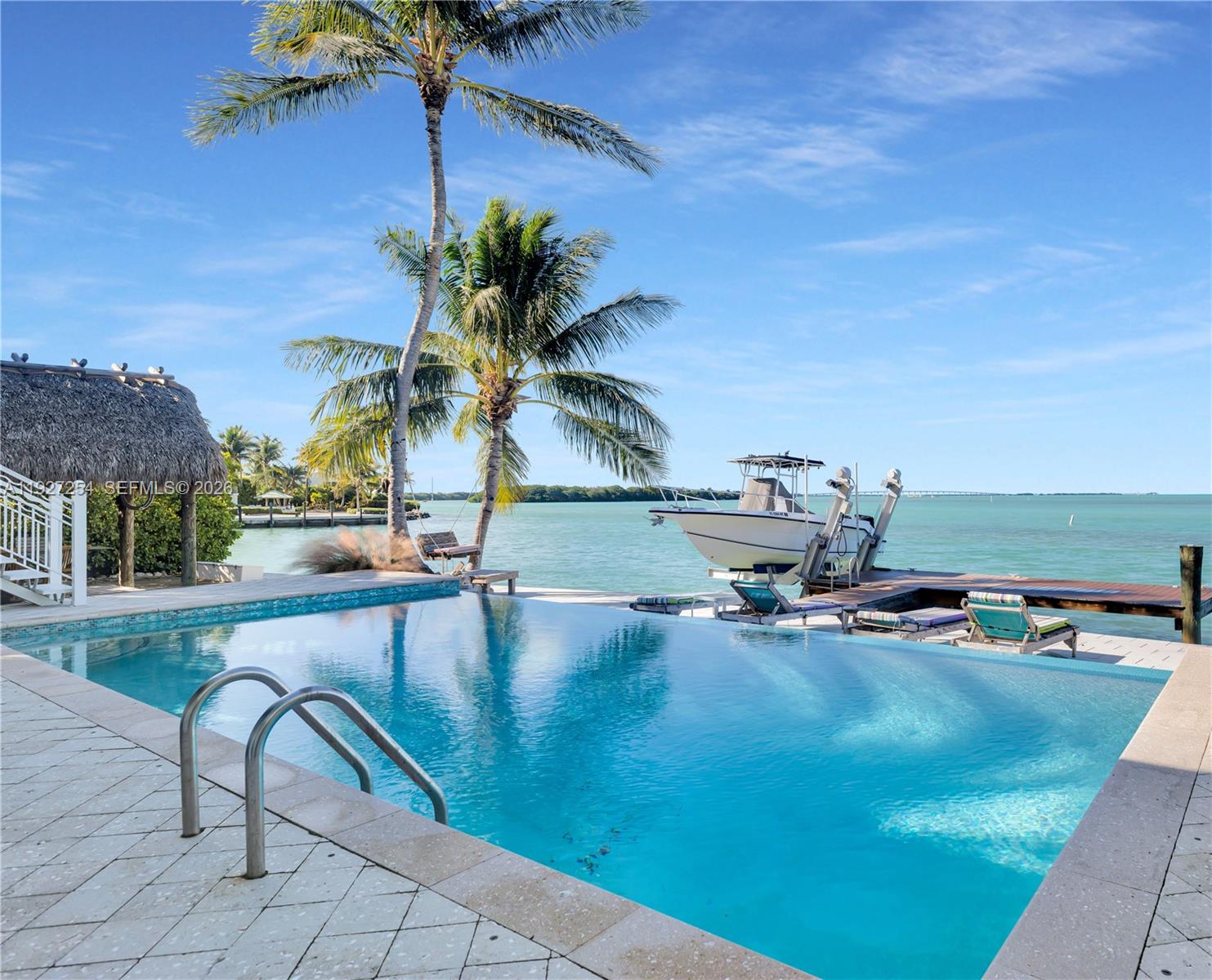 Welcome to 166 Bayview Drive, a rare bayfront estate in the prestigious Safety Harbor neighborhood of Lower Matecumbe Key. Located at Mile Marker 74, this property offers direct access to Florida Bay and the Atlantic Ocean, placing you in the heart of Islamorada's world-class boating and sportfishing scene. The home enjoys unobstructed water views and nightly sunsets that paint the sky in brilliant hues. A Tiki at the water's edge provides a perfect perch for morning coffee or evening cocktails, while mature landscaping adds privacy and tropical charm. Boaters will appreciate the deep-water dockage with davits, ideal for quick access to open water. The 2,478-square-foot residence features 4 bedrooms and 4 bathrooms, with tile flooring throughout and expansive windows that frame the bay. The open-concept living and dining areas flow into a well-appointed kitchen. The primary suite offers direct water views and private outdoor access. Outdoor living is elevated with a spacious pool and deck area, balcony, and brick paver walkways. The white picket fencing and lush landscaping complete the coastal aesthetic. Additional features include CBS construction, off-street parking, FKAA water service, septic system, and low HOA fees. Pets are welcome. Whether you're seeking a full-time residence, seasonal retreat, or investment opportunity, 166 Bayview Drive delivers unmatched location, views, and lifestyle in the Florida Keys.