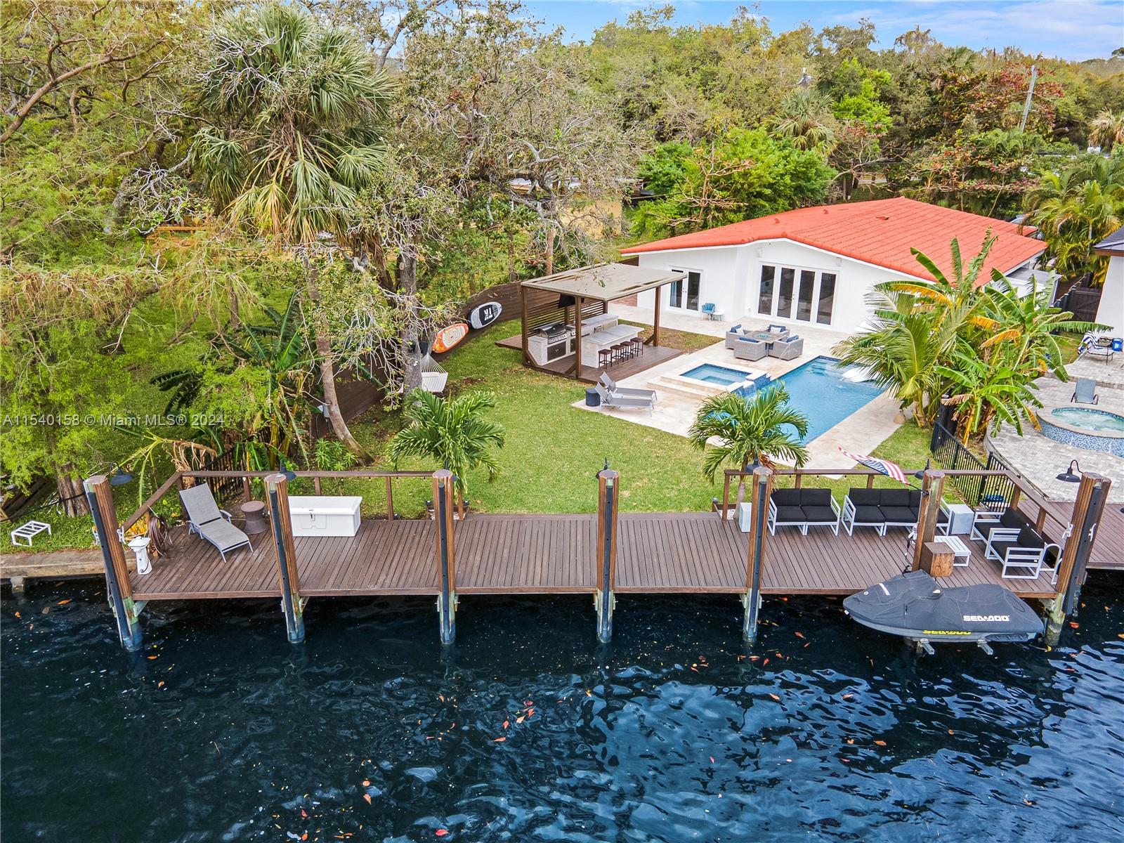 Welcome to your waterfront paradise. This meticulously renovated home offers a luxurious retreat with a 60-foot deepwater dock, perfect for boating enthusiasts. The outdoor space is an entertainer's dream, featuring an outdoor kitchen, JetSki lift, solid wood privacy fence heated saltwater pool surrounded by travertine tile, hot tub and a full Sonos surround sound system. The property boasts an array of modern amenities including impact windows, new AC, a $70,000 kitchen renovation  w/brand new appliances, porcelain wood-look tile, recessed lighting, vaulted ceilings, renovated bathrooms and bedrooms... all adding to the allure of this stunning home. This property offers the perfect blend of luxury and functionality. Don't miss the opportunity to call this remarkable residence your own.