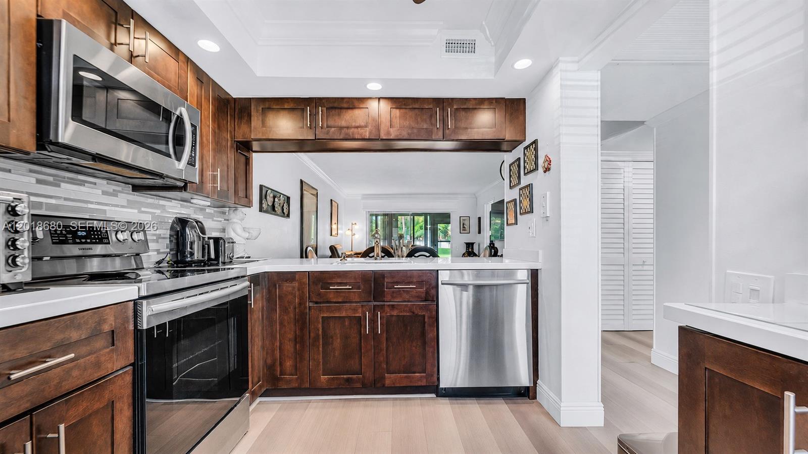 Beautifully customized ground-floor 2 bedroom /2 bath residence in Wynmoor’s Nassau Village, designed for effortless 55+ living with no stairs and turnkey convenience. This move-in-ready retreat offers a warm, sophisticated interior with rich wood-look wide plank flooring throughout and an open living/dining area that feels spacious, refined and inviting.

The designer kitchen blends espresso shaker cabinetry, white quartz countertops, a gray glass mosaic backsplash, stainless steel appliances, recessed lighting and a crown-molding tray ceiling. Both bathrooms have been tastefully reimagined with modern vanities and spa-inspired finishes.

Enjoy added peace of mind with impact doors and hurricane shutters. Located in Wynmoor, one of Coconut Creek’s most sought-after active adult communities, residents enjoy resort-style amenities including golf, pickleball, tennis, heated pools, fitness facilities, clubhouse activities, live entertainment, social clubs, guard-gated security and courtesy transportation. Close to shopping, dining and South Florida beaches.