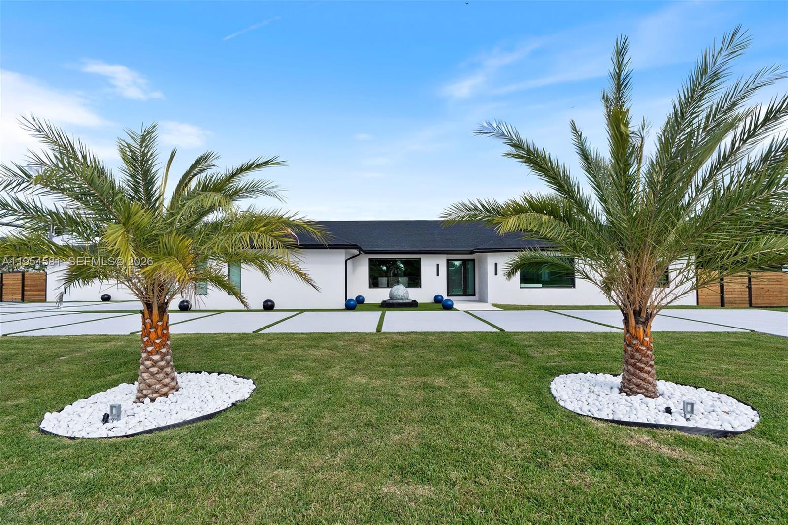 Welcome to an extraordinary residence where contemporary design meets unparalleled outdoor living — a sanctuary reimagined from top to bottom on an expansive corner lot. Fully remodeled with no detail spared, this home offers a rare blend of refined interiors and unmatched outdoor living, setting a new benchmark for luxury in the area. The home makes an immediate impression with all-new Low-E impact windows and doors, enhancing both aesthetics and energy efficiency while flooding the interior with natural light. Inside, expansive living areas are unified by 48×48 Spanish porcelain tile, creating a clean, contemporary canvas throughout. The heart of the home is a designer kitchen and living space finished with Taj Mahal quartzite countertops, offering timeless elegance, durability, and visual warmth. Every space has been thoughtfully reimagined to maximize flow, comfort, and functionality. Designed for elevated entertaining and everyday enjoyment, the property opens to a private outdoor oasis that includes a heated smart pool and jacuzzi with app-controlled functionality, a custom pickleball court with professional lighting, and an exterior cabana equipped with a Summerset BBQ and premium appliances delivering a true resort-style experience at home. Manicured landscaping is supported by a sprinkler system. Additional features include a 2-car garage, integrated whole-home audio system, and a modern camera security system.