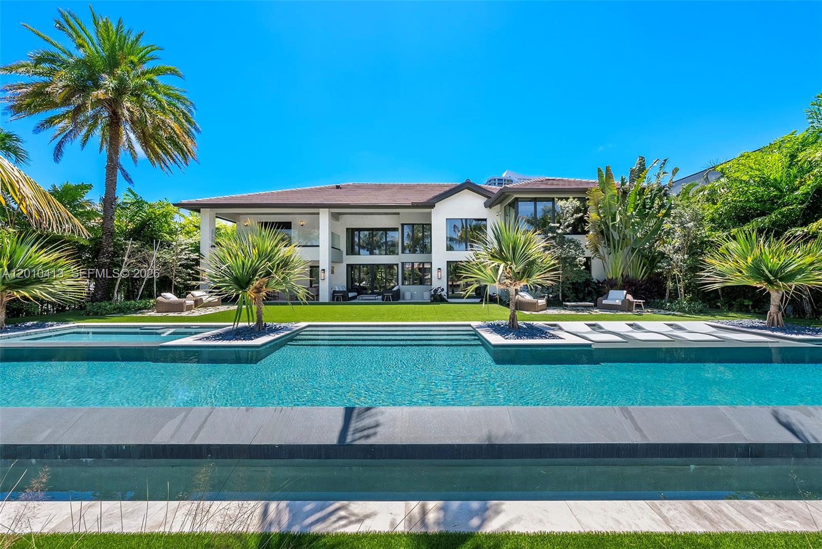 Welcome to 110 Holiday Dr in Golden Isles, a tropical modern estate curated by Pietra Casa Studio in one of South Florida’s most central waterfront neighborhoods. This sprawling residence is perfectly positioned on the lot, with soaring ceilings, a seamless family layout, and an 80 ft resort-style pool that anchors the outdoor living. Warm, bold design is expressed through white shell limestone, Tundra Grey marble, and rich natural textures throughout. Interiors feature Italian marmorino plaster, bespoke oak and marble furnishings, handmade lighting, and a Mia Cucina kitchen with Inalco slabs, SubZero and JennAir appliances. A fully realized design experience, inside and out.
