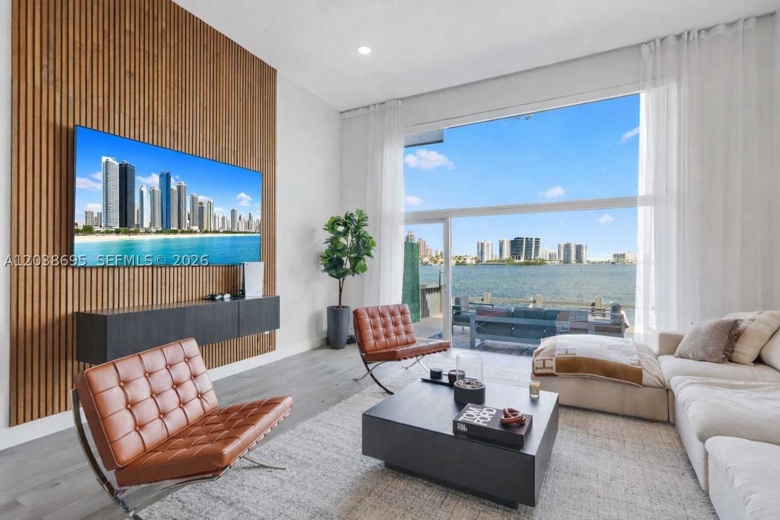 This residence captures the essence of Miami waterfront living. A rare multi-level flat offering a sophisticated yet serene lifestyle with panoramic bay views visible through floor-to-ceiling glass on every level. Water and skyline become the backdrop to everyday living. The open split-level layout creates a dramatic yet comfortable flow between the living, dining, and kitchen areas, all oriented toward the bay. The residence features 3 bedrooms, two and a half bathrooms. The layout is designed to maximize natural light, openness, and a strong connection to the water. Outdoor living is equally impressive. A spacious bi-level waterfront deck extends from the living area to a private dock space with a boat lift, creating a seamless indoor-outdoor setting ideal for entertaining or relaxing by the bay. Additional highlights include a full balcony and a private garage for added convenience and privacy. Located in the guard-gated community of Eastern Shores with 24/7 patrol by North Miami Beach Police, residents enjoy both tranquility and security, along with direct ocean access via Haulover Inlet with no fixed bridges.