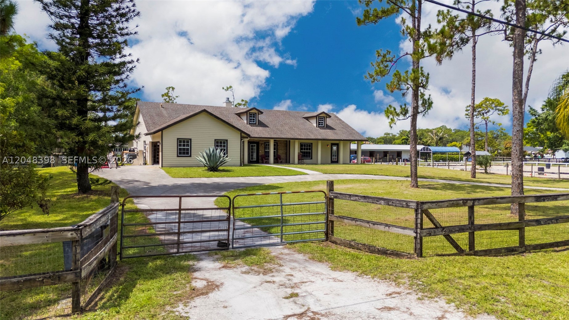 Experience the perfect blend of privacy, space, and convenience on this beautifully maintained 1.25-acre fully fenced property, ideally located near the entrance of The Acreage just off Mango Road for easy access in and out of the community. This spacious home features soaring high ceilings, 3 bedrooms, 2 bathrooms, and a generous primary suite complete with dual vanities, a spa tub, separate shower, and an oversized walk-in closet. The inviting living room is anchored by a stunning floor-to-ceiling stone fireplace, entire interior freshly painted, while the covered front porch, attached 2-car garage, and long concrete driveway add to the home's curb appeal and functionality. A standout feature that is attached private MOTHER-IN-LAW SUITE with its own entrance, separate bedroom, living area, kitchenette, and full bathroom, ideal for multi-generational living, guests, or potential rental income. Outside, enjoy the freedom of The Acreage lifestyle with a two-stall horse stable and plenty of room for horses, boats, RVs, trailers, gardens, or future additions, all with NO HOA. Conveniently located near parks, equestrian trails, shopping, dining, highly rated Palm Beach County schools, Florida's Turnpike, I-95, Palm Beach International Airport, Wellington's world-renowned equestrian venues, championship golf, and beautiful beaches. Enjoy the perfect balance of peaceful country living and everyday convenience.