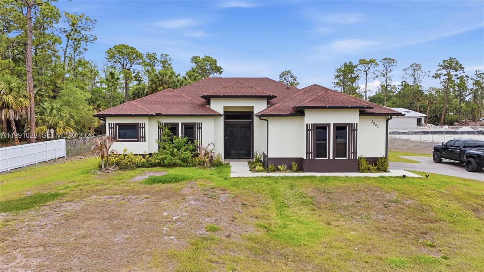 Golden Gate Estates home on 2.75 acres featuring a split-bedroom layout, a spacious kitchen with ivory soft-close cabinets and beautiful countertops, plus a office room. Enjoy high ceilings and recessed lighting throughout. The property offers a large covered patio, garage, and a fully fenced lot with a private entrance. The grounds have been prepared for parking—perfect for an RV, boat, or semi-truck. Impact windows throughout for added security and efficiency.
