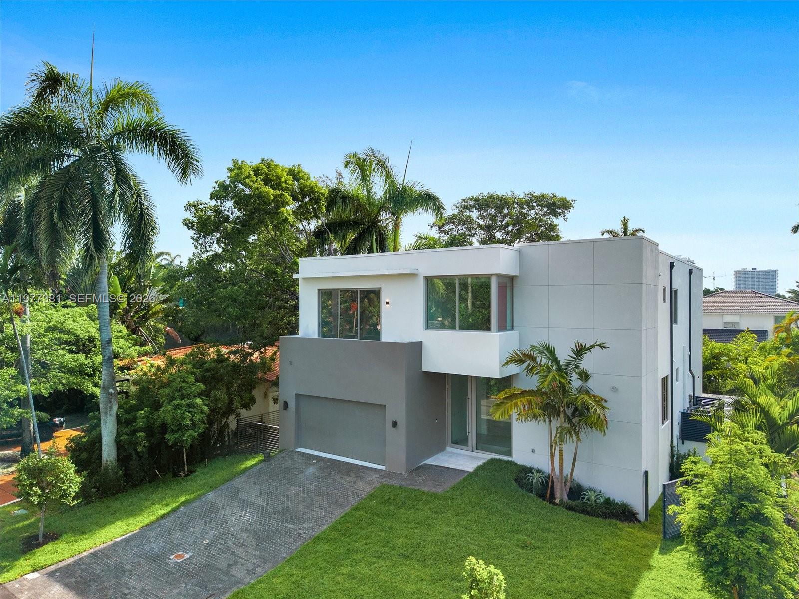 Discover this stunning new construction home in North Bay Village, thoughtfully designed for modern living. The residence features five spacious bedrooms, five full bathrooms, and an additional half bath across 4,410 square feet of beautifully crafted space.
The sleek contemporary exterior is complemented by expansive windows that flood the home with natural light. Inside, the open-concept layout is highlighted by floor-to-ceiling glass walls that showcase lush greenery and create seamless access to the private pool and patio—perfect for relaxing or entertaining guests.
Clean architectural lines run throughout the home, while the kitchen serves as a true centerpiece with a striking marble island and elegant fixtures that add a touch of everyday luxury. On track for April 15th completion.