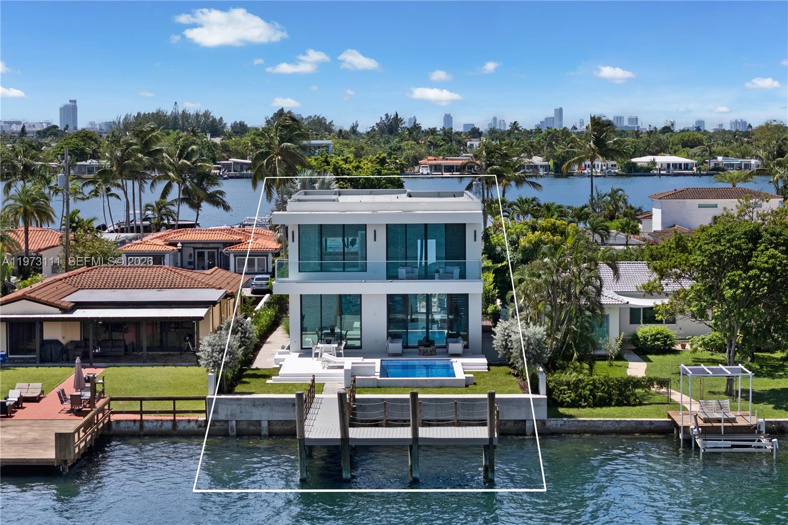 Exceptional new construction waterfront residence in a prestigious gated community with ocean access and bay views. This 5BD/5.5BA two-story home features a bright, open layout with floor-to-ceiling windows for natural light. The chef’s kitchen includes custom cabinetry, granite countertops, Thermador and Miele appliances, wine cooler, and mini fridges. The expansive primary suite offers a private terrace, dual walk-in closets with custom built-ins, and a spa-style bath with dual sinks, soaking tub, and shower. All other bedrooms are ensuite with built-in closets; one has a private terrace. Enjoy indoor-outdoor living with a heated saltwater pool, spacious patio, and a summer kitchen, perfect for entertaining, along with a private dock. Additional highlights include a 2-car garage, ample driveway parking, and elevated finishes.