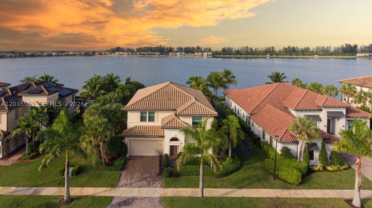 Welcome to this exceptional two-story Mediterranean residence, beautifully positioned on the largest lake in Parkland, offering breathtaking panoramic waterfront views that define true South Florida living. This was one of the model homes, the setting delivers a rare sense of openness, serenity, and water-focused lifestyle that few homes can match. With approximately 4,462 square feet of total construction, this elegant home features a bright, open floor plan enhanced by soaring ceilings and abundant natural light. A grand foyer entry leads to formal living and dining areas, a private den, an expansive family room, and a dedicated laundry room—designed for both comfort and entertaining. The kitchen is a standout, showcasing custom cabinetry, built-ins, a refined butler’s area, and a walk-in pantry, seamlessly blending function and style. Architectural highlights include refined finishes, sophisticated lighting fixtures, and a dramatic wood staircase complemented by a striking stone accent wall. The residence offers 4 spacious bedrooms, 3.5 bathrooms, and generous walk-in closets, providing comfort and privacy throughout. Outdoors, enjoy a beautifully fenced backyard with unobstructed lake views—your own tropical retreat ideal for relaxing, entertaining, and taking in unforgettable sunsets. This is a rare opportunity to own a waterfront home with iconic lake views, timeless Mediterranean design, and an elevated lifestyle in one of Parkland’s most desirable communities.