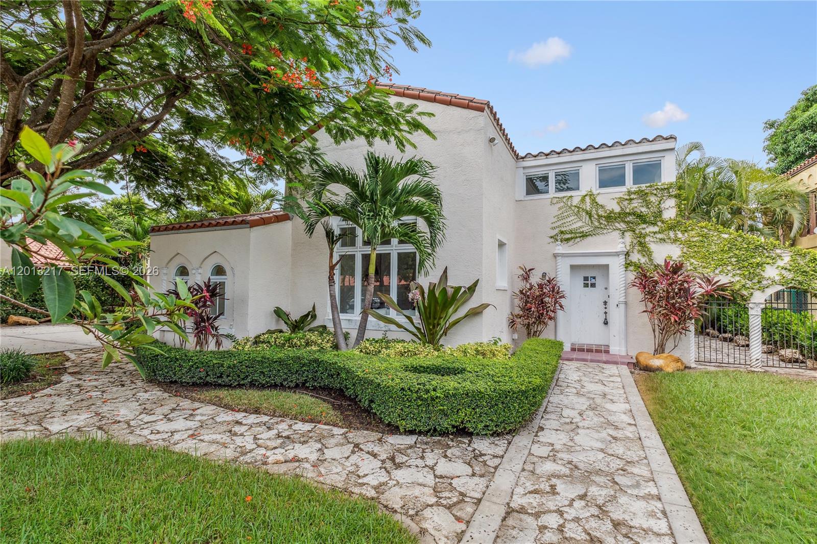 Nestled on a lush 13,917 SF lot, this captivating 2-story gated residence in the heart of Coral Gables offers 5,123 SF of meticulously crafted living space, featuring 6 bedrooms and 4.5 bathrooms. Step inside to discover a home rich in character, showcasing original 1920s Cuban tile floors, Pecky Cypress doors, and coffered ceilings that add timeless charm throughout. A formal foyer welcomes you into an impressive grand room with soaring double-height ceilings. The one-of-a-kind kitchen features a central island and opens seamlessly to a lovely outdoor dining area, perfect for entertaining. The expansive owner’s suite serves as a true retreat, complete with a private office, meditation room, walk-in closet, and a spa-like bathroom featuring a steam shower and jacuzzi.
Outside, the property continues to impress with hurricane impact windows and doors, a beautifully manicured oversized garden, a heated pool, and a jacuzzi—offering the ultimate South Florida lifestyle.