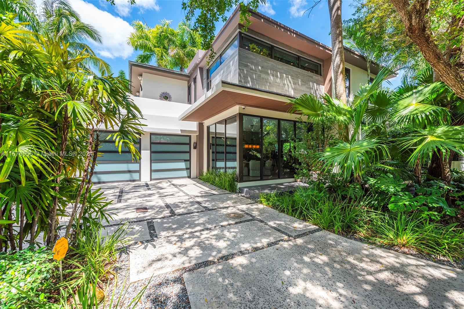 Modern Miami intersects w/Old Grove in this contemporary masterpiece framed by mature palms, oaks & lush gardens. Stately entry showcases dramatic 550-btl wine cellar. Soaring ceilings, porcelain floors, glass & Venetian plaster walls & expansive windows comprise the flowing interiors. Smarthome technology integrates premium Sound System & Lutron Lighting/Shades. Flr 1: Sublime Living & Dining rms; sleek, GE Monogram Kitchen w/breakfast bar; Guest suite; Laundry; dbl Garage. Flr 2: 4 en suite Bdrms (gorgeous Primary w/walk-in closet, elegant bath, private toilet, triple-waterfall shower, soaking tub, dbl vanities & wide N balcony); bonus S balcony.  Exterior: Grandly scaled covered Terrace; Pool; full-house generator. Idyllic, luxurious, effortless SoFla living 5 minutes to downtown Grove