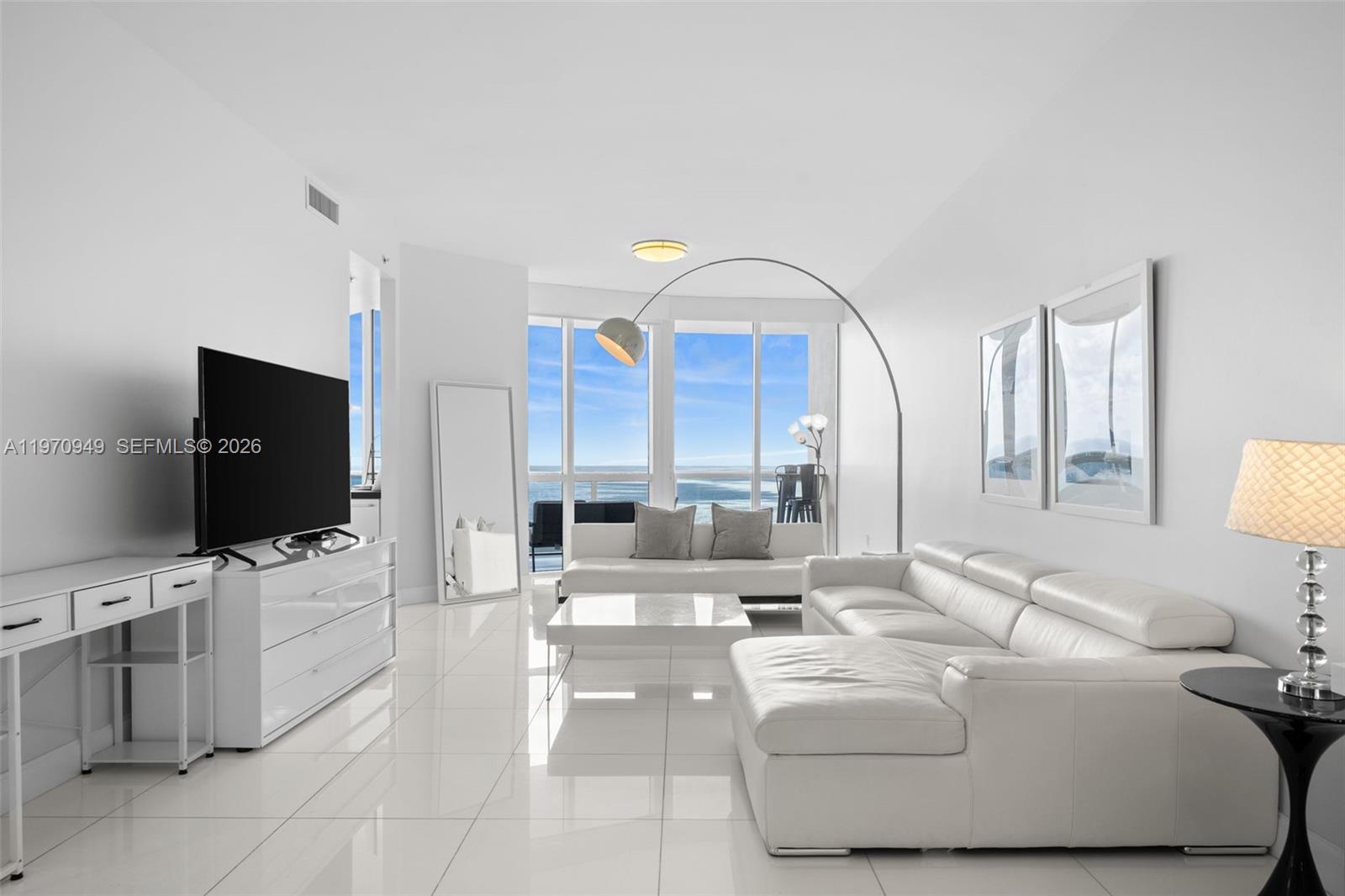 Experience elevated oceanfront living in this stunning 2-bedroom, 2.5-bath residence offering 1,722 square feet of refined interiors at the prestigious Trump Royale Condo. This beautifully appointed unit showcases a bright, open-concept layout with floor-to-ceiling windows framing breathtaking, unobstructed views of the Atlantic Ocean. Glossy white tile floors and a crisp, modern aesthetic create a light-filled, sophisticated ambiance throughout the main living areas. The spacious living and dining areas flow seamlessly to expansive glass walls. The sleek kitchen features contemporary cabinetry, stainless steel appliances, a built-in oven and microwave, and a large island with cooktop and overhead hood—ideal for both everyday living and entertaining. A charming breakfast nook set against panoramic ocean views provides the perfect setting for morning coffee. The generously sized primary suite offers a serene retreat with ample closet space and a spa-inspired en-suite bath. The second bedroom also features its own private bathroom, ensuring comfort and privacy for guests. A convenient half bath serves the main living area. Located in the highly sought-after Trump Royale, residents enjoy five-star resort-style amenities including beachfront service, pool and spa, state-of-the-art fitness center, tennis courts, concierge, valet, and 24-hour security.