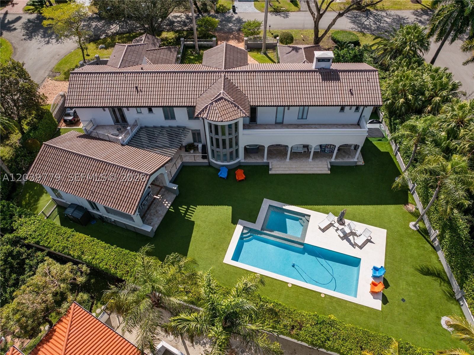 Around the corner from Islands of Cocoplum's tennis courts and resort-style amenities, the crown jewel of Paloma Drive awaits. Situated on an oversized corner-to-corner 20,823 SF lot with exceptional privacy and only one rear neighbor, this renovated estate blends timeless elegance with modern luxury. Remodeled in 2016 and upgraded throughout the years, the residence features a new roof (2025), HURD impact glass, Sonos audio, and Lutron smart systems. Offering 8,569 total SF with 6 bedrooms, 5 full baths, and 1 half bath, the home is designed for entertaining and everyday living. Soaring ceilings, custom millwork and garden views define the formal living and dining spaces. The gourmet kitchen showcases Viking and Miele appliances, a Calacatta marble island, custom cabinetry, and opens to the breakfast area and family room. A temperature-controlled wine cellar and butlers panty enhances the home's entertaining appeal.The primary suite features dual custom closets, 2 additional closets, and a spa-inspired bath. Upstairs are a den and two en-suite suites, while two downstairs bedrooms offer flexibility. Additional features include 1/1 staff quarters on the mezzanine level, AC storage areas, a fireplace, motorized shades, a circular drive, and a two-car garage.
Outdoor living is equally impressive, with a heated pool, covered terraces, mature tropical landscaping, and exceptional privacy in one of Coral Gables' most coveted neighborhoods.