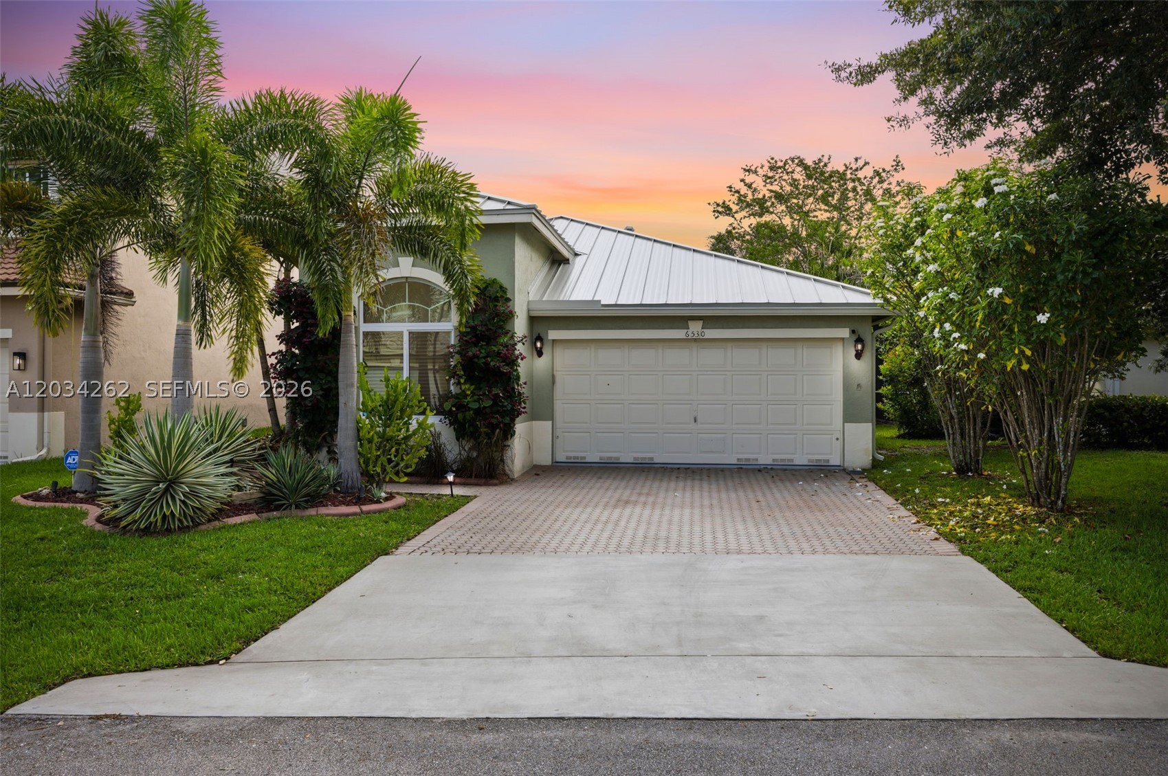 LAKEFRONT LIVING AT ITS FINEST IN REGENCY LAKES! Welcome to this beautifully maintained 3-bedroom, 2-bath home with one of the community's most desirable features: a breathtaking wide-water lake view that creates the perfect backdrop for everyday living and entertaining. This move-in ready home features a spacious floor plan and numerous recent upgrades, including a new metal roof (2025), seamless gutters (2025), impact windows and doors, upgraded bathrooms, customized closets, motorized blinds, resurfaced garage floor, fully screened and tiled patio with sun setter retractable awning. Rachio Wi-Fi irrigation system, Wi-Fi garage door and two stage energy efficient Trane AC system. The third bedroom has been customized as a home office, providing flexibility for today's lifestyle. Additional improvements include fresh interior paint, updated landscaping, irrigation enhancements, security cameras, and premium appliances.  Located within the highly sought-after Regency Lakes community, residents enjoy a guarded gated entrance, impeccably maintained grounds, resort-style pool, fitness center, pickleball courts, tennis courts, basketball court, volleyball court, and community Wi-Fi. Conveniently located near shopping, dining, parks, major highways, and top-rated schools, this home offers the perfect combination of comfort, security, and South Florida lifestyle.  Wake up to sparkling lake views and enjoy the best of Regency Lakes living. This is one you won't want to miss!