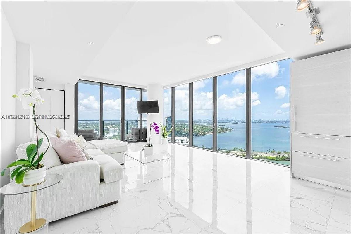 Corner residence with floor-to-ceiling windows wrapping the entire living space, flooding the home with natural light that carries through into the bedroom and bathroom. Elevated throughout with upgraded designer flooring selected from the developer’s premium collection, paired with light contemporary cabinetry that is both refined and rarely available in the building. Thoughtful built-ins add function and style in the bedroom, complemented by a fully customized walk-in closet with generous storage. Enjoy sweeping water views from every angle and a private balcony positioned to capture both sunrises over the bay and sunsets across the skyline. A residence that balances clean design, comfort, and views in one of Edgewater’s most desirable addresses. Set within an ultra-luxury, full-service building offering an unmatched amenity collection including a full-size bowling alley, tennis courts, golf simulator, cigar lounge, spa and wellness facilities, business center and resort-style pool deck. The community is anchored by a waterfront boardwalk, neighborhood dog park, and on-site waterfront dining, creating a true live-work-play atmosphere right outside your door.
