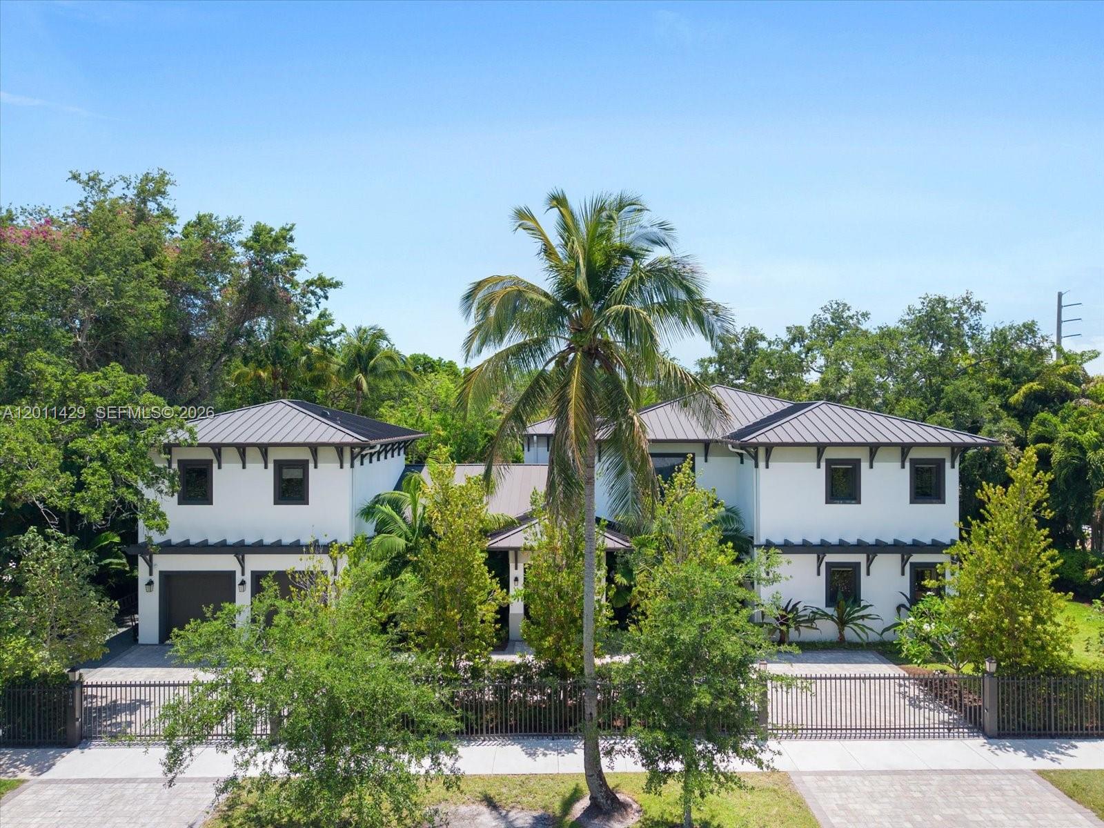 Located in the highly desirable Baptist district, this exceptional tropical modern estate sits on a 15,052 SF lot and offers 7 BD, 6 BA, sophisticated design, and resort-style living. A grand dual-entry driveway and wood-paneled entry porch lead into dramatic interiors featuring soaring vaulted ceilings, recessed lighting, and expansive open-concept living spaces. The great room seamlessly integrates the living, dining, wet bar, breakfast area, and designer kitchen, with sliding glass doors opening fully to the outdoor terrace for effortless indoor-outdoor living. The chef’s kitchen is appointed with custom cabinetry, quartz countertops and backsplash, a large center island, secondary prep sink, and premium Wolf, Sub-Zero, Miele, and Asko appliances. Outdoors, enjoy a striking geometric heated pool with waterfall feature and spa finished in teal mosaic tile, surrounded by a travertine deck, lush tropical landscaping, artificial turf, and a fully equipped summer kitchen with Wolf grill and Big Green Egg. The upstairs primary suite is a luxurious retreat with private terrace, wet bar, custom walk-in closets, and spa-inspired bath with dual vanities, Roman tub, frameless double shower, and dual smart water closets. Additional highlights include a private guest/in-law apartment, elevator, dedicated office, upstairs laundry, Savant smart home automation, ADT security, four A/C units, and a 2-car garage. A rare luxury offering in one of Kendall’s most sought-after locations.