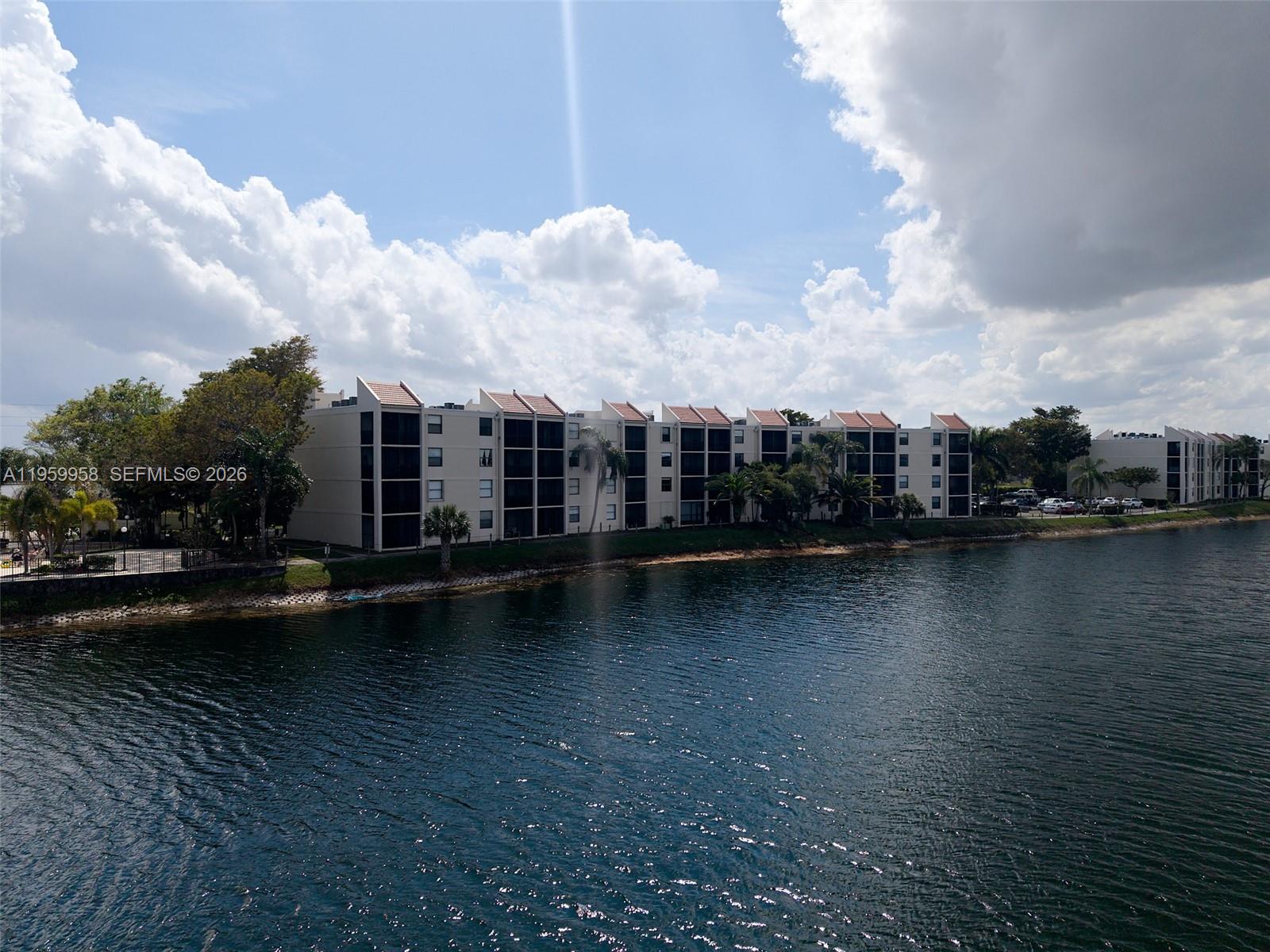 Beautiful 2-bedroom, 2-bath lakefront residence offering serene water views and a spacious private balcony—perfect for enjoying your morning coffee or unwinding at sunset. The thoughtfully designed layout provides comfortable living spaces, abundant natural light, and a peaceful waterfront ambiance throughout. Located in an affordable, well-maintained community, residents enjoy an array of resort-style amenities, including three sparkling swimming pools, a fully equipped fitness center, clubhouse, tennis and basketball courts, and scenic picnic areas ideal for relaxing or entertaining. On-site management and 24-hour guard-gated security provide added convenience and peace of mind. Cable and internet are included in the maintenance fee, and small pets are welcome. Enjoy the unique perk of on-site restaurant service available on weekends and special occasions. Additionally, this building shares the same power grid as the nearby fire station, allowing for quicker power restoration during storms or outages. The unit features partial accordion hurricane shutters on the front-facing windows (kitchen and front bedroom). The primary bedroom window and both balcony sliding glass doors (living room and bedroom) are not equipped with shutters. Whether you’re looking for a full-time residence or seasonal retreat, this lakefront gem offers comfort, security, and exceptional value.