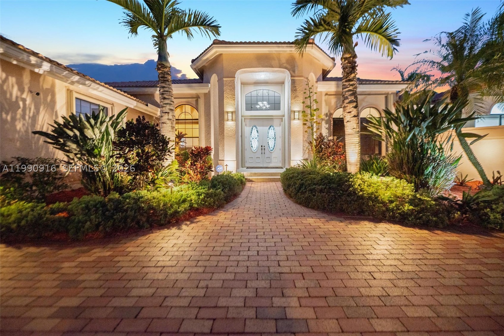 This elegant residence is set on a private oversized corner lot within the prestigious guard-gated community of Palm Island in Weston. Granite floors enhance the main living areas, while rich hardwood flooring elevates the bedrooms, adding warmth and comfort to the home’s private spaces. Soaring ceilings create bright, open interiors designed for both comfortable living and refined entertaining, offering balance, privacy, and an everyday retreat atmosphere. Thoughtful upgrades throughout include motorized Hunter Douglas Silhouette blinds, custom California Closets, and beautifully finished bathrooms with top-of-the-line fixtures. The private primary suite features tranquil pool views, a spa-inspired bath. Spacious family bedrooms, office/den, guest suite, home gym, and custom Finlandia sauna, thoughtfully designed to support relaxation and well-being at home. The gourmet kitchen showcases premium appliances including Sub-Zero, Dacor, and Viking, paired with Amadeus granite countertops and custom cabinetry. Step outside to a tropical oasis featuring a heated saltwater pool, spa, screened patio, and lush landscaping ideal for year-round entertaining or peaceful outdoor living. The home also includes integrated built-in and stand-alone surround A/V systems for an enhanced entertainment experience, a Garage-Tec finished garage, and fully integrated smart-home technology. Located near top-rated schools, parks, dining, shopping, houses of worship, and major highways.