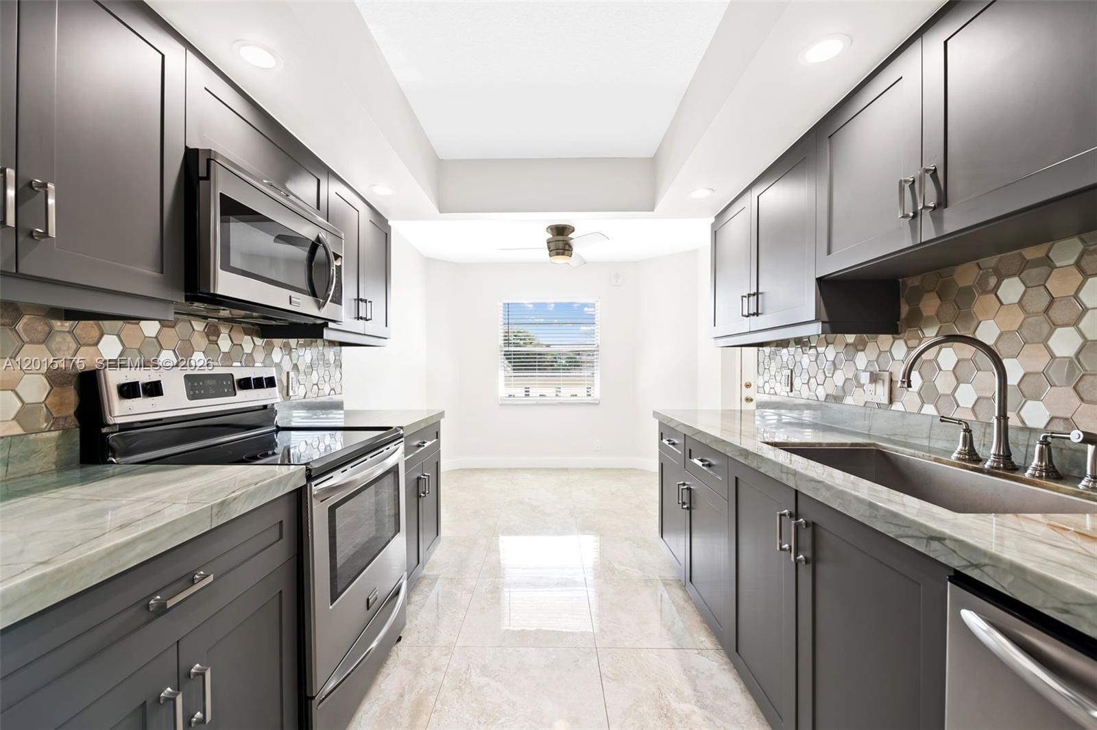 Beautifully renovated and move-in ready, this light-filled residence offers modern design and serene surroundings at Wynmoor 55+ Community. Featuring rectified tile flooring throughout, updated kitchen with custom cabinets, stainless steel appliances, stone countertops, and geometric tile backsplash. A dedicated dining area sits just off the kitchen, ideal for both everyday living and entertaining. The spacious living room opens to an enclosed patio with tranquil lake and water fountain views—perfect for relaxing or enjoying your morning coffee. Both bedrooms are generously sized, including a primary suite with a large walk-in closet and an updated en-suite bath. Bathrooms are tastefully finished with modern vanities, frameless glass showers, and elegant tilework. Conveniently located just off the Avenue of the Stars, this unit is steps from the theater, fitness center, and two swimming pools. Additional features include a brand new in-unit washer and dryer, assigned parking, and a large storage unit on the same floor. AC replaced in 2023 and water heater in 2017. Quietly situated within a well-kept building, this turnkey home offers comfort, style, and an unbeatable location.