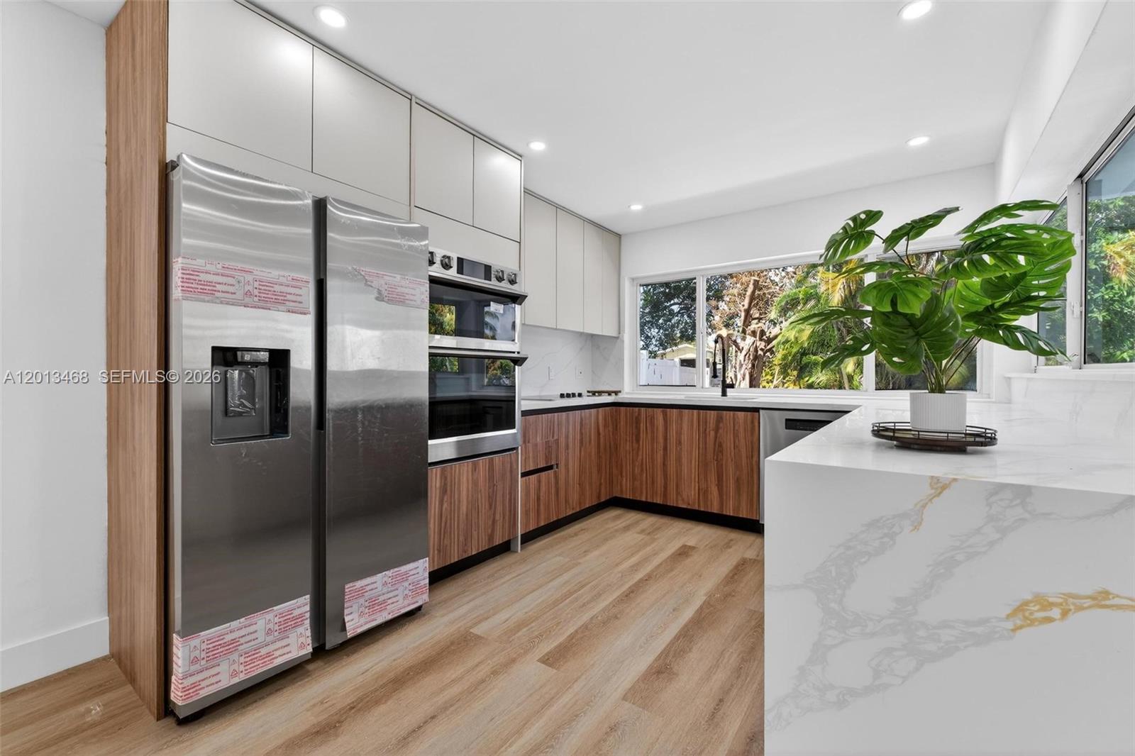 Fully renovated waterfront pool home in Miramar Isles, 3 bed 2 bath, sitting right on the canal. The mid-century curb appeal was preserved, the original breeze block screen at the entry is intact and a head-turner. Open layout with a beautiful kitchen: waterfall calacatta-style quartz with gold veining, walnut lower cabinets, white flat-panel uppers, double wall ovens, cooktop, and full stainless package including a side-by-side fridge with water and ice. Two designer bathrooms with doorless walk-in showers, walnut slat feature walls, hexagon mosaic floors, and matte black fixtures. Wide-plank wood-look LVP flooring throughout, recessed LED lighting, and a walnut slat divider that anchors the entry. Roof 2024, full impact windows and doors, fresh paint inside and out. Backyard has a resurfaced pool with new mosaic waterline tile, white aluminum safety fence, and a private canal-front deck with artificial turf and direct water views. Minutes from I-95, the Turnpike, Hard Rock Stadium, schools, and shopping. Move-in ready.