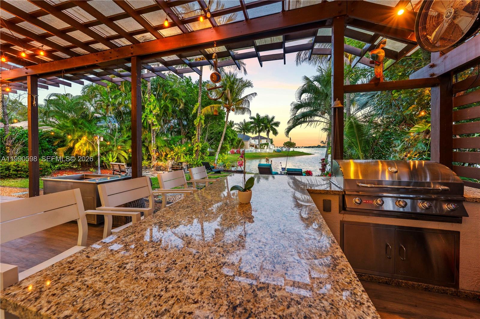 Just imagine if you could have luxury, comfort, & breathtaking views blend seamlessly in your dream Waterfront Villa. Imagine no more! Perfectly situated on an OVERSIZED PREMIUM LOT with pristine designer landscaping, an elegantly tiled terrace along with a dream outdoor kitchen, bar, & grill area that overlook a majestic lake, creating the perfect setting for unforgettable gatherings and peaceful evenings unwinding in the sunset. Inside, the expansive layout flows effortlessly with Soaring Volume Ceilings rare for a single story home and a beautiful array of oversized impact windows & doors throughout the home allowing for tons of natural light & positive energy. The primary suite serves as a private sanctuary with panoramic views of lush tropical landscaping and glimmering water frontage. Its spa inspired bath features a soaking tub & a custom shower with an integrated sauna, offering the full spa experience. The designer kitchen captivates, showcasing soaring cabinetry highlighted by one of a kind Rare Natural Quartzite Stone Countertops-Backsplash-& Oversized Island with direct water views from your kitchen! The entire home is equipped with a Reverse Osmosis Water-Filtration system. Beyond your private oasis,enjoy resort-style amenities including a lakefront pool with a cascading waterfall, basketball, tennis,pickle ball court,a fitness center, & more! Surrounded by A+Schools this dream home is waiting for your family to call it home and won't last!