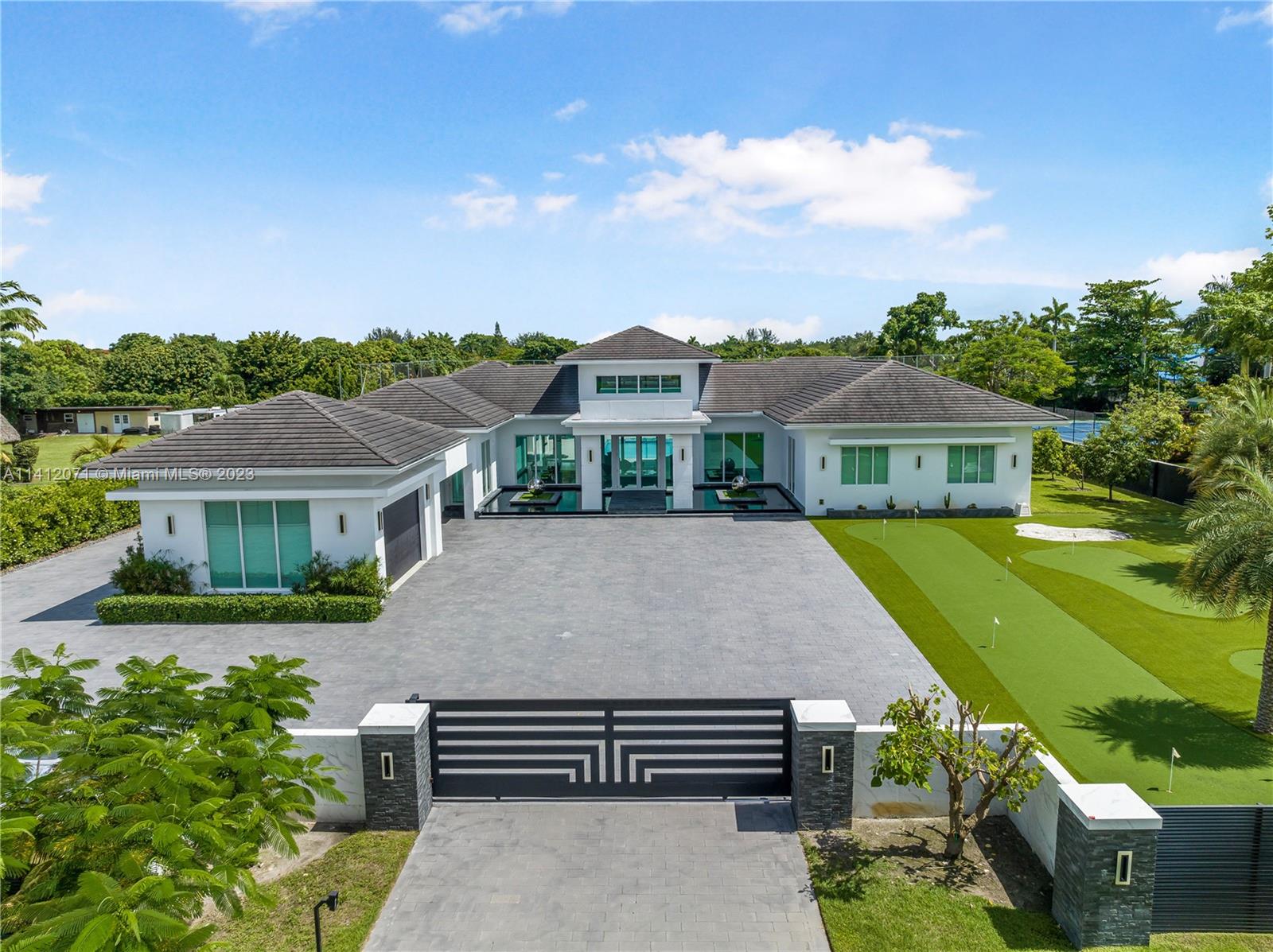 Built in 2023, no expense was spared in crafting this residence, using only the finest materials and finishes. Professionally decorated, the interior exudes a modern and elegant charm. The house features impact windows and high-quality porcelain 36x72 floors extend throughout. The Mia Cucina kitchen boasts high-end Subzero Wolf appliances. Equipped with 2 A/C units and an intelligent house system with Savan automation. Step outside to discover an infinity-edge saltwater pool, complete with a heater, spa, stunning glass tile accents, and a gazebo with a fully equipped kitchen. Professional turf has been thoughtfully installed, creating a soccer field and mini golf course. Outdoor speakers from Coastal Source and interior Klipsch speakers.