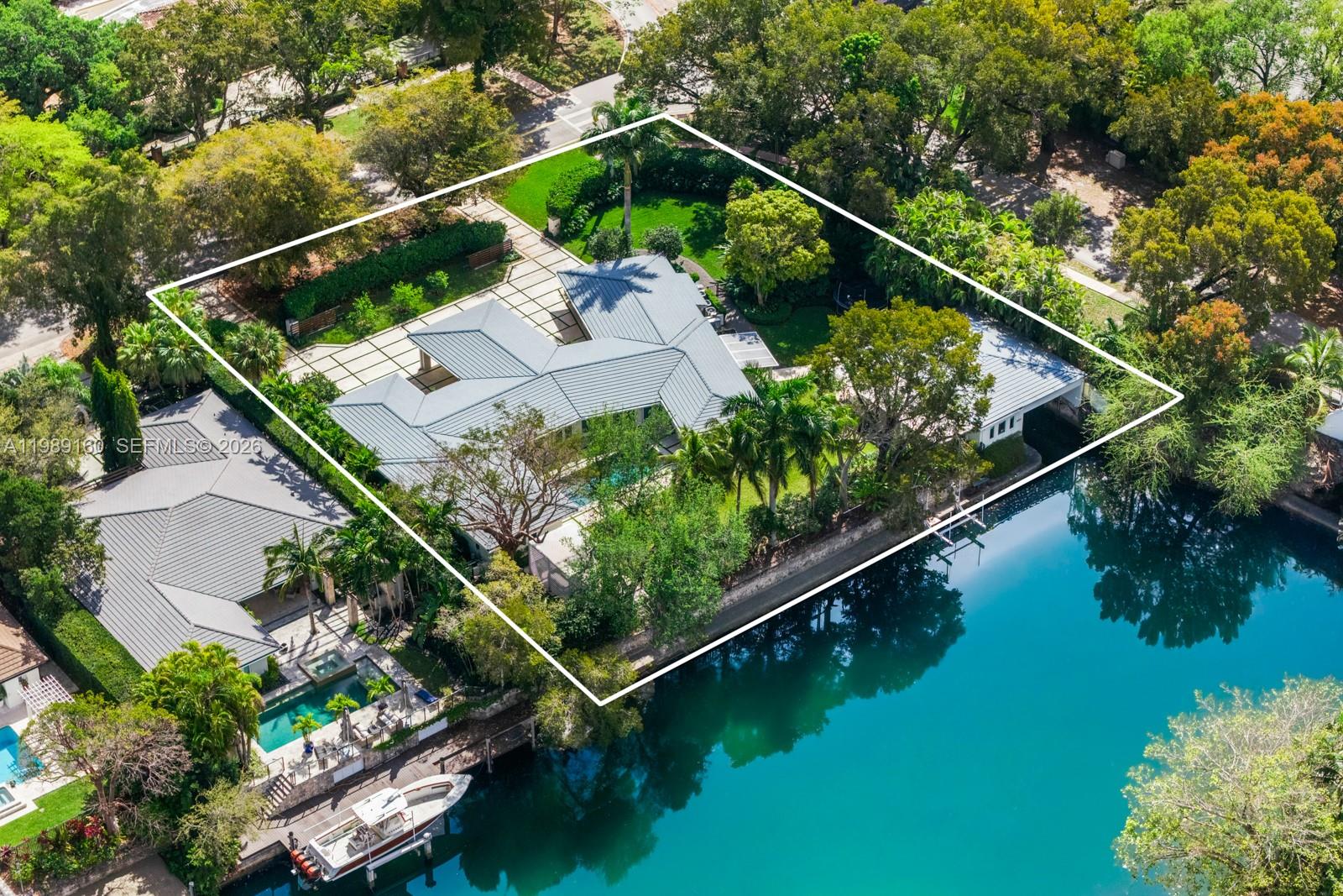 One of only 27 homes with a true covered boathouse along the coveted Coral Gables Waterway, this stunning modern estate features 3BD/3.5BA in the main residence, plus a 2BD/1BA guest house with direct boathouse access. Set on a 27,125 SF lot with 175 FT of prime water frontage, the property offers an expansive backyard with pool, cabana, lush greenery, and multiple outdoor entertaining spaces overlooking the water. The primary suite is a private sanctuary with marble bath, dual sinks, rainfall glass shower, soaking tub, and a large walk-in closet with built-ins. Sun-drenched interiors, sleek modern finishes, and multiple living and entertaining areas complement a porte cochere, 2-car garage, gated driveway, and abundant natural light throughout, delivering an unmatched Coral Gables waterfront lifestyle.