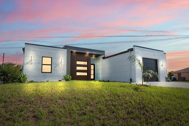 CO IN HAND. READY TO MOVE IN. Premium CORNER LOT 10 minutes from I-75 & 5 minutes from Publix. This upgraded model offers modernist architecture, irrigation/gutter systems, paver driveway, and custom landscaping with exterior lighting. Interior upgrades: tray ceilings, LED, PVC cladding, and level 4 drywall. The kitchen features a quartz waterfall island, two-tone CUSTOM cabinets. Bathrooms offer walk-in showers with glass doors and a double sink in the master. Additional features: impact windows, CUSTOM closets, 1.5-car garage with epoxy flake flooring, and smooth stucco exterior. Same model available at 702 Irving Ave N, Lehigh Acres – completion Aug 2025. Note: Though the home has a flat-roof look, it has a standard 4/12 sloped pitch—no concerns with leaks, insurance, or standing water.