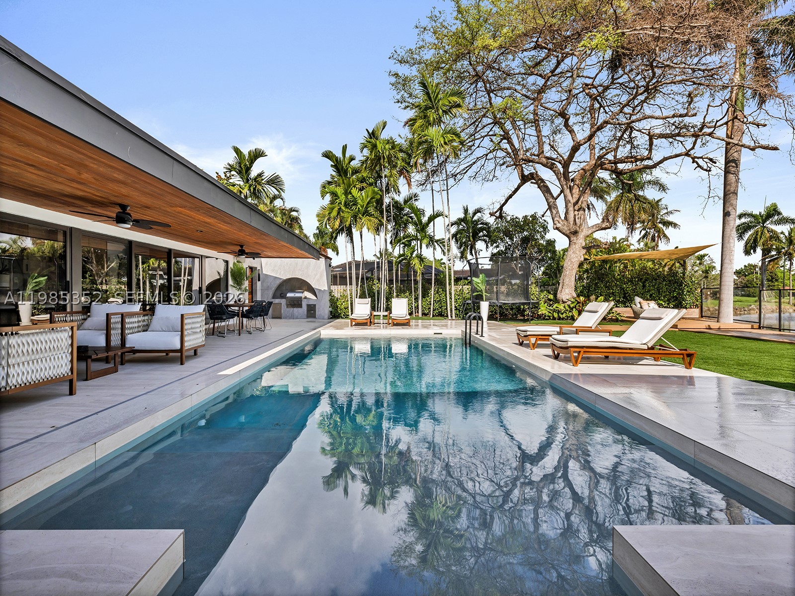 Fully reimagined modern residence built by the principal of META Development on a rare canal-front lot in prime N. Palmetto Bay, minutes from Pinecrest. Set on 14,947 SF with serene waterway views, this 4-bed, 3.5-bath home spans 4,323 SF adjusted area and was completely transformed in 2025 with designer-level finishes. The open-concept floor plan is thoughtfully framed by custom millwork and sophisticated LED lighting, resulting in a space that feels both contemporary and timeless. The chef's kitchen features custom cabinetry, a book-matched porcelain waterfall island, Samsung appliances, wine and beverage refrigerators, and Hansgrohe fixtures. The primary suite offers a spa-inspired bath with soaking tub and an oversized, fully built-out walk-in closet. Custom built-ins extend through the kitchen, pantry, bar, closets, and baths delivering both function and artistry. A metal roof, new electrical panel, AV system, and two EV charging outlets complete the package. Outside, a covered wood-ceiling loggia opens to a heated pool and lush lawn along the canal, framed by palms and a clear fence; a true private oasis. Near top-rated schools, parks, and the best of Palmetto Bay and Pinecrest.