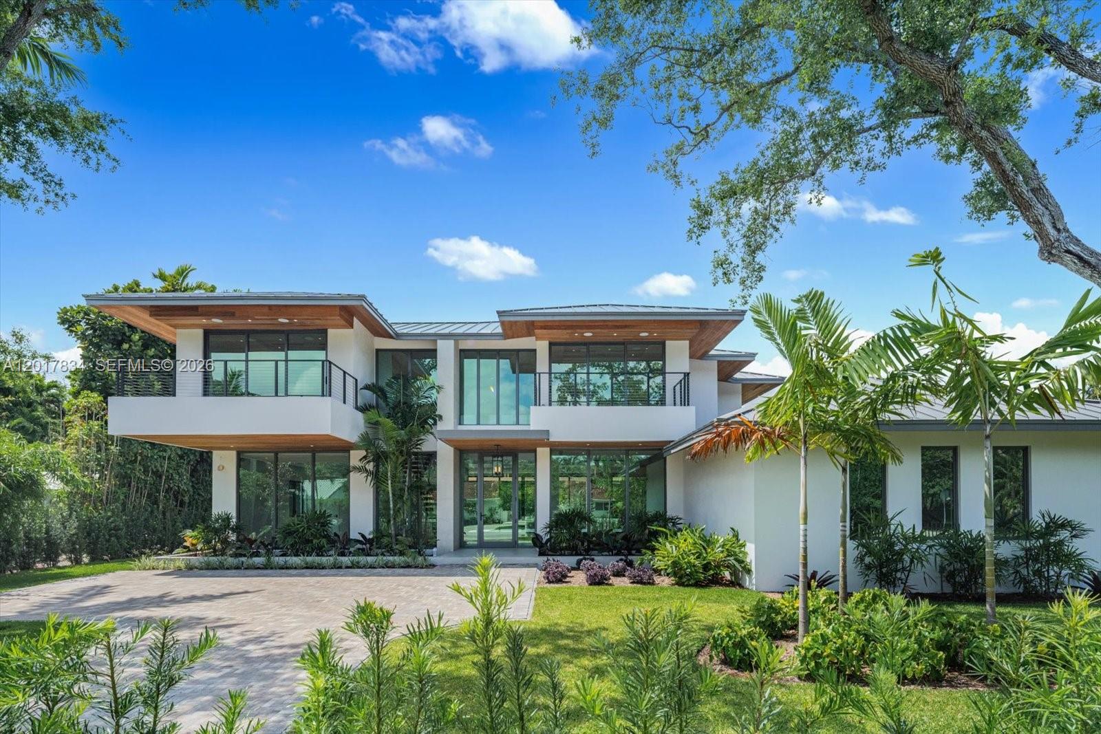 Experience elevated tropical modern living in this newly constructed South Miami residence offering 6,426 total SF with 5 bedrooms, 5.5 bathrooms, on a prime 15,158 SF corner lot. Defined by contemporary architecture, soaring ceilings, walls of glass, and warm wood detailing, the home blends luxury and functionality. The open-concept layout features expansive living and dining areas, porcelain flooring downstairs, white oak floors upstairs, and a floating glass-and-wood staircase. The gourmet Italian kitchen showcases custom cabinetry, an oversized marble waterfall island, premium Fulgor appliances, a 6-burner gas range, and a temperature-controlled wine cellar with over 280-bottle capacity. Floor-to-ceiling sliding glass doors open to a resort-style outdoor retreat with a covered terrace, summer kitchen, heated saltwater pool with integrated spa, full cabana bath, lush landscaping, and landscape lighting throughout. Upstairs, the luxurious primary suite features a sitting area, private covered terrace overlooking the pool, and a spa-inspired bathroom with dual floating vanities, soaking tub, and oversized glass shower. Additional highlights include en-suite bedrooms with private terraces, a junior suite on the main level, separate staff quarters, 3-car garage, smart home wiring, three A/C units, and ample driveway parking. Ideally located moments from parks, shopping, and dining, this exceptional property offers modern luxury and convenience in the heart of South Miami.