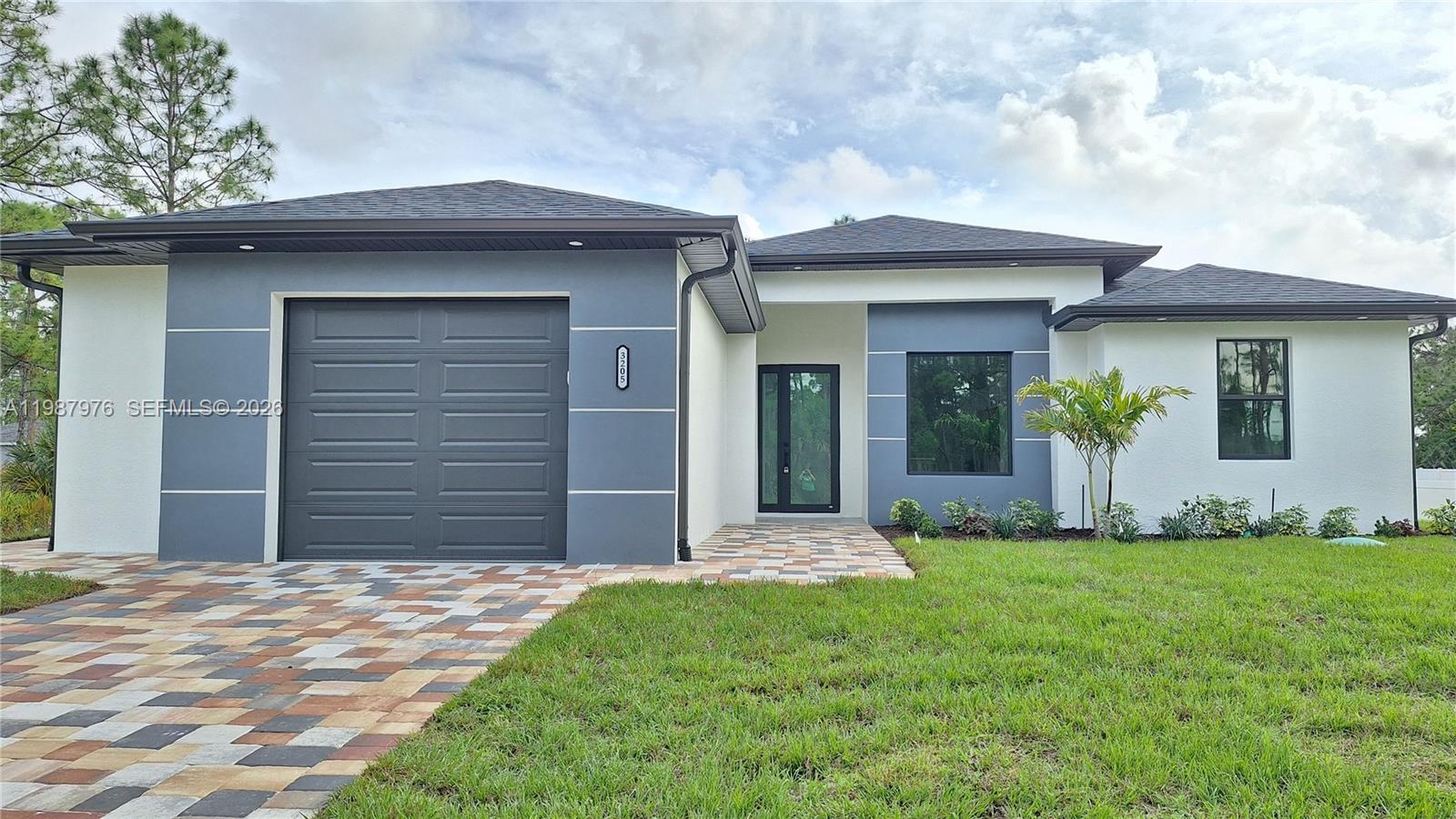 Beautiful NEW CONSTRUCTION located in a quiet and growing area of Lehigh Acres! This modern home features 10-foot ceilings and tile flooring throughout the entire house, offering a bright, open, and elegant living space. The open-concept layout connects the spacious living and dining areas with a stylish kitchen featuring quartz countertops, center island, and pantry, perfect for everyday living and entertaining. The master bedroom offers a comfortable retreat with dual sinks, TWO walk-in closets, and a spacious shower. Impact-resistant windows provide added safety, durability, and energy efficiency. Additional functional features include a utility sink in the garage and another sink in the lanai area, providing extra convenience for cleaning, gardening, or outdoor use. Exterior highlights include a paver driveway and entry, automatic irrigation system, and peaceful wooded area views that provide added privacy. This move-in ready home is conveniently located near schools, shopping, restaurants, and major roads, offering the perfect balance of comfort, style, and accessibility. Don't miss the opportunity to own a brand-new home in one of Lehigh Acres’ fastest-growing areas.