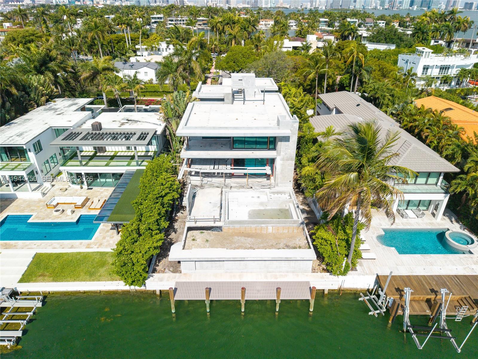 Luxury waterfront home being built with dramatic evening views of the Miami Beach skyline. Designed by Praxis Architecture, this 5 bed 5 and 1/2 bath home has 5,400 sq foot of living space under AC, with an additional 2,600 sq foot of understory with 9 foot height clearance for parking 5 cars, gym, storage area, games. Open floor plan with sliding telescopic doors for effortless indoor-outdoor living. Expansive primary suite includes a private covered patio. Featuring exquisite French oak flooring, marble bathrooms, this home offers a refined blend of elegance and functionality. The property boasts a covered summer kitchen, pool, dock with lift, and a rooftop terrace providing uninterrupted 360-degree views. Completion expected winter 2026.