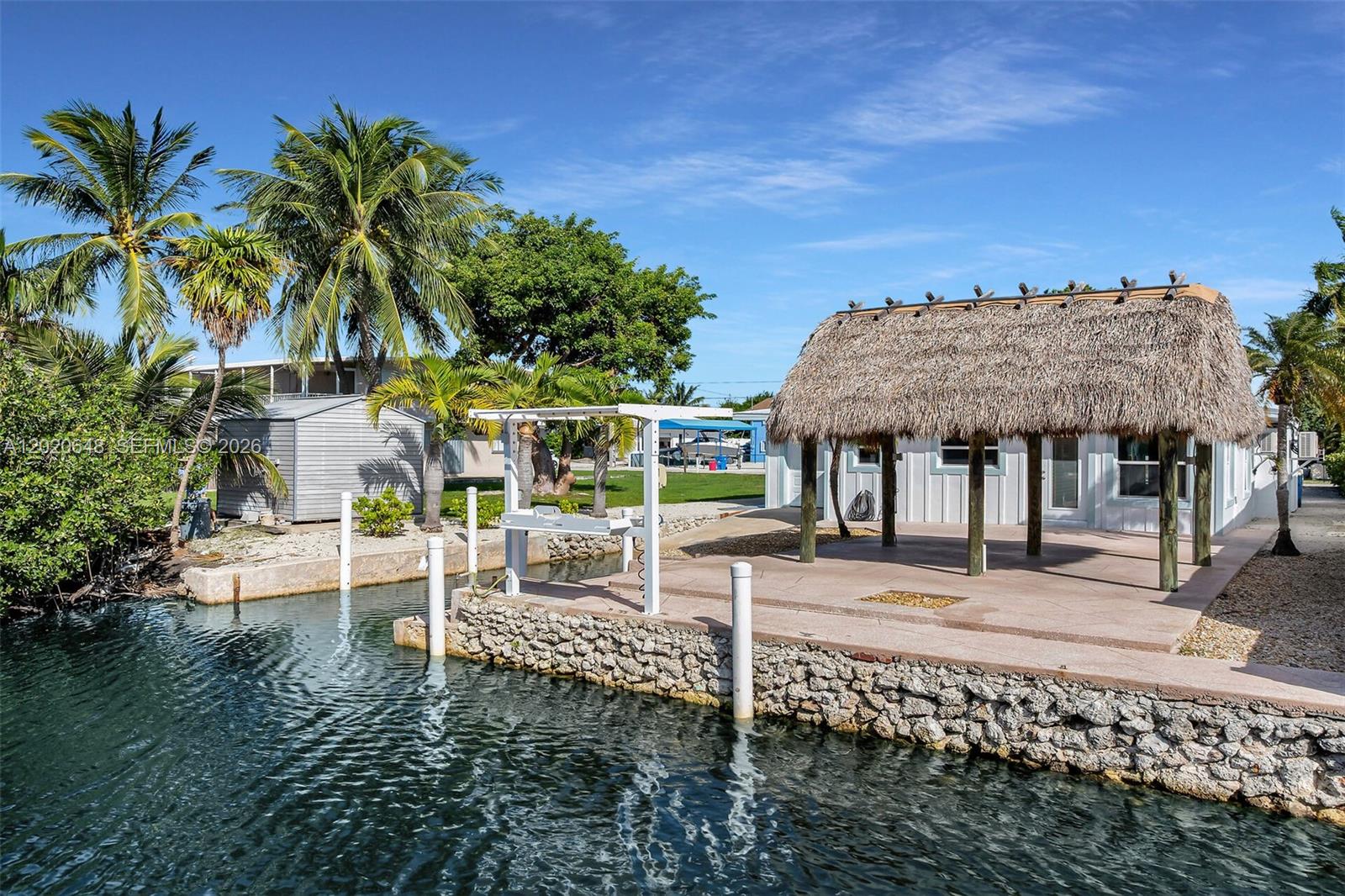 Located on a tranquil canal-front setting in the desirable Plantation Key Colony, this impeccably updated, turnkey ground-level residence offers two bedrooms, two baths, 50 ft of coveted dockage, and boat slip with immediate bay access. Meticulously maintained and ready for carefree island living. The home's concrete, ground-level construction enhances both durability and ease of maintenance, while a fresh, clean aesthetic unfolds inside and out. Recent upgrades and improvements include brand new metal roof, impact windows and doors, new interior and exterior paint, new interior doors, energy efficient appliances, new sewer line, and re-thatched tiki hut. Updates to the attached pull through garage includes new door rollers, lock hardware, and upgraded flooring and wall finishes, all designed to keep the property in turnkey condition. This home is for those who embrace water-based recreation with easy bay and ocean access via Tavernier Creek, a boat slip with ramp through the garage, and new fish cleaning station with electric and water hookup. The voluntary homeowners association offers a bayfront HOA park with a new boat ramp, beach, and picnic area. With its ideal location and exceptional features, this canal home presents a unique opportunity to embrace the vibrant lifestyle of the Upper Keys.