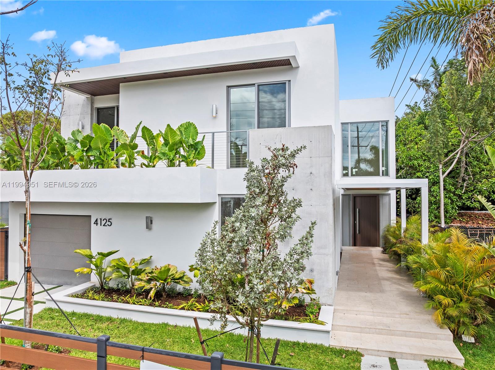 Welcome to OWN Development’s Mega Home, presented by The Azar Team. This exceptional new construction two-story residence offers 4,328 square feet under air and a total of 5,256 square feet of thoughtfully designed living space. Blending modern architecture with functional elegance, the home features 4 bedrooms, a home office, and 4.5 bathrooms, including a full bedroom and bath on the first floor, ideal for guests. A dramatic foyer sets the tone upon entry, leading into an open-concept layout with high ceilings in the main living areas. The seamless flow between the living room, family room, and kitchen creates a bright and inviting atmosphere, enhanced by recessed lighting. Additional flexible spaces include an open den on the first floor and a second den upstairs. The centrally positioned kitchen features Taj Mahal quartzite countertops and backsplash, Thermador appliances, a walk-in pantry, and a clean, modern design. Upstairs, the primary suite offers a private retreat with an en-suite bathroom, while the remaining bedrooms are well-proportioned. Engineered hardwood flooring runs throughout the second floor, adding warmth and a refined finish. The outdoor space is designed for entertaining, featuring a private pool with a heater and salt chlorination system, covered patio, and landscaped yard. The home is fully fenced and includes an automatic gate, CCTV, and surround sound. A balanced layout in prime Miami, close proximity to the Design District.