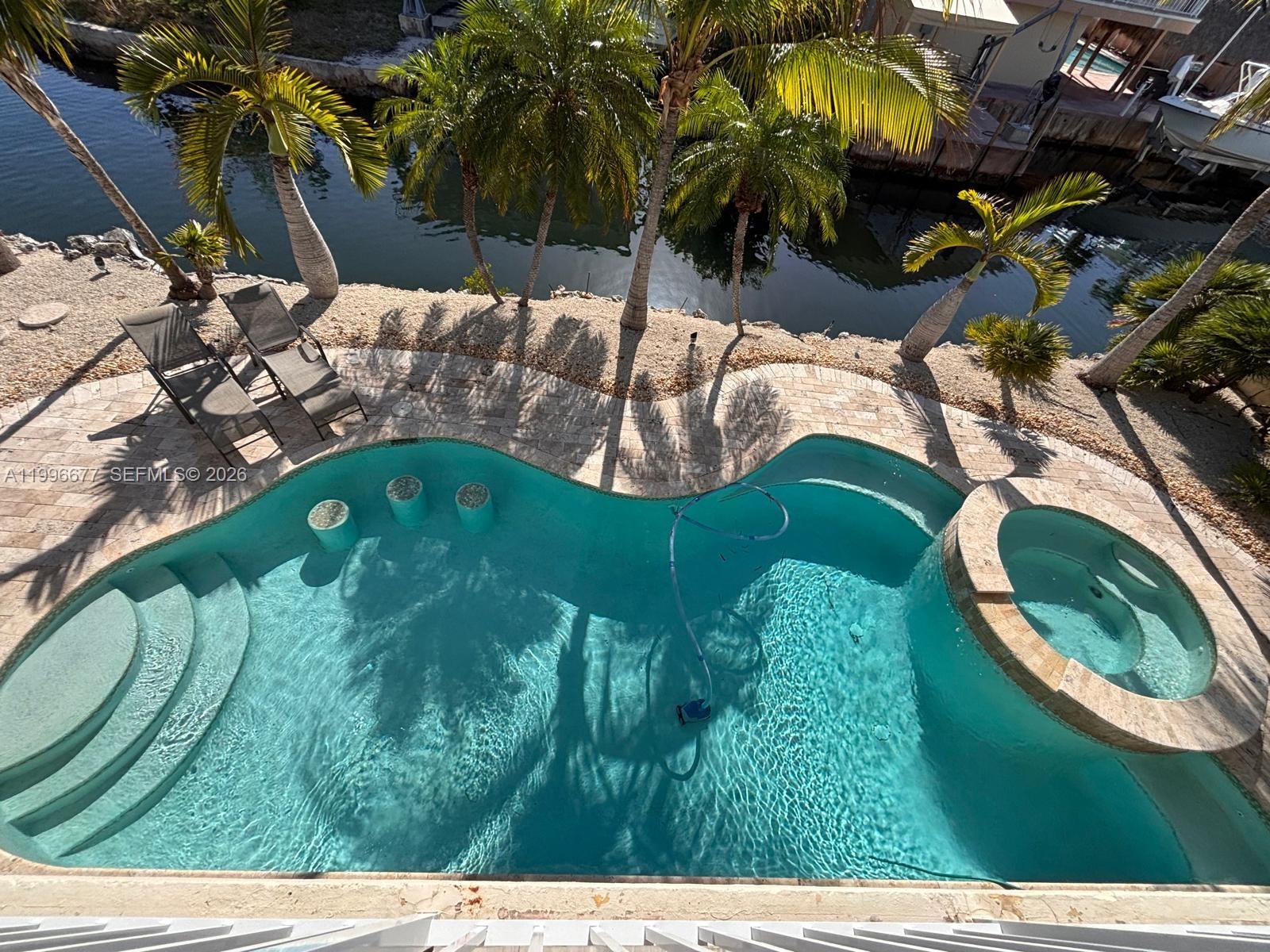 Waterfront oceanside home in Key Largo, Florida on a point lot on a main deep-water canal featuring 200 feet (120 feet x 80 feet) of water frontage with deep-water docking with 80 feet of dock space, a 15,000 pound boat lift in a cut in slip for your boat just minutes from the open ocean with a beautiful underground pool and hot tub. This tropical paradise sits on an oversized point lot at the end of a private street on a cul-de-sac.
