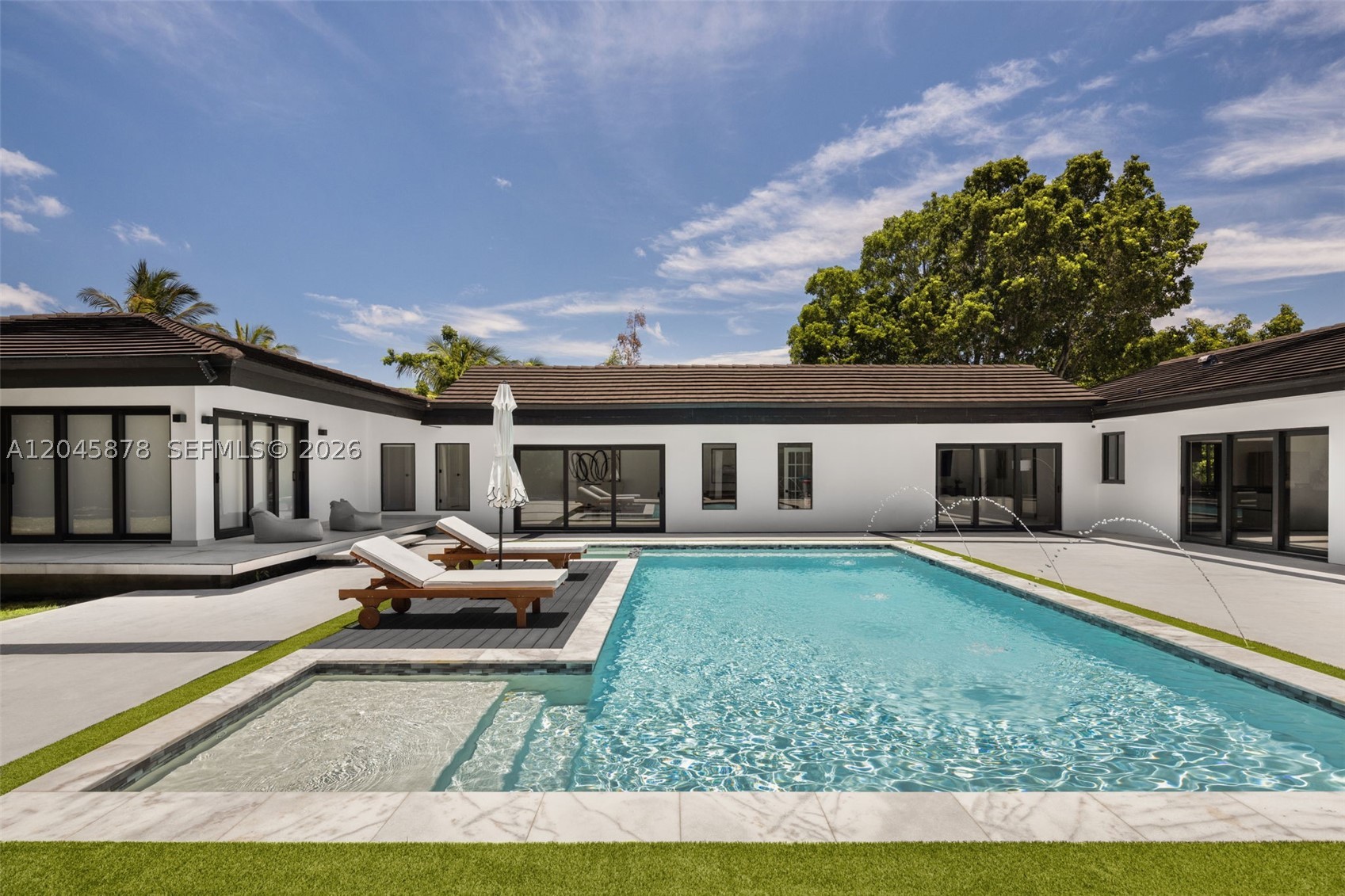 Set on nearly an acre in the prestigious enclave of Sun Grove Estates, this fully renovated estate offers a rare combination of privacy, scale, and timeless modern architecture. Reimagined in 2021, the residence features an impressive footprint with expansive, light-filled living spaces, multiple gathering areas, and an open split-bedroom floor plan designed for effortless everyday living and entertaining. Floor-to-ceiling windows and doors throughout create a seamless connection to the outdoors, where a resort-style pool, an expansive covered and open terrace, and lush green spaces provide the ideal setting for year-round enjoyment. The luxurious primary suite is a private retreat featuring soaring vaulted ceilings, walls of sliding glass overlooking the pool and gardens, and a spa-inspired bath with a private terrace. A detached guest house with a bedroom, bathroom, and kitchenette offers exceptional flexibility for extended stays or private accommodations. Additional highlights include a new roof, new plumbing, a new pool, a circular driveway, two additional external storage rooms, and a fully gated entrance. Ideally located near top-rated schools, this exceptional property offers refined indoor-outdoor living in one of Miami's most desirable neighborhoods.
