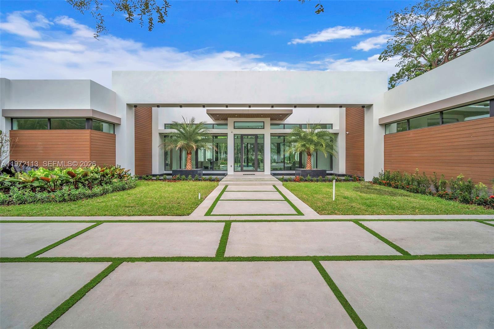 Completed in December 2025, this modern luxury residence sits on an expansive 34,000 SF corner lot, offering exceptional privacy and a quiet setting. The single-story home spans 6,658 SF and features 12-foot ceilings throughout, with a dramatic 16-foot ceiling in the main living area. The home offers 5 bedrooms, each with its own walk-in closet, and 6 full bathrooms. Designed for both everyday comfort and entertaining, the chef’s kitchen is equipped with Wolf and Sub-Zero appliances, a hidden walk-in pantry, and a stunning glass-enclosed wine cellar. Oversized 48” x 48” porcelain flooring flows throughout the home, complemented by porcelain finishes in all bathrooms. Additional features include a 3-car garage with 12-foot ceilings and the potential for car lifts, a concrete roof, speaker and camera system throughout and top-tier impact windows, providing durability, energy efficiency, and peace of mind.